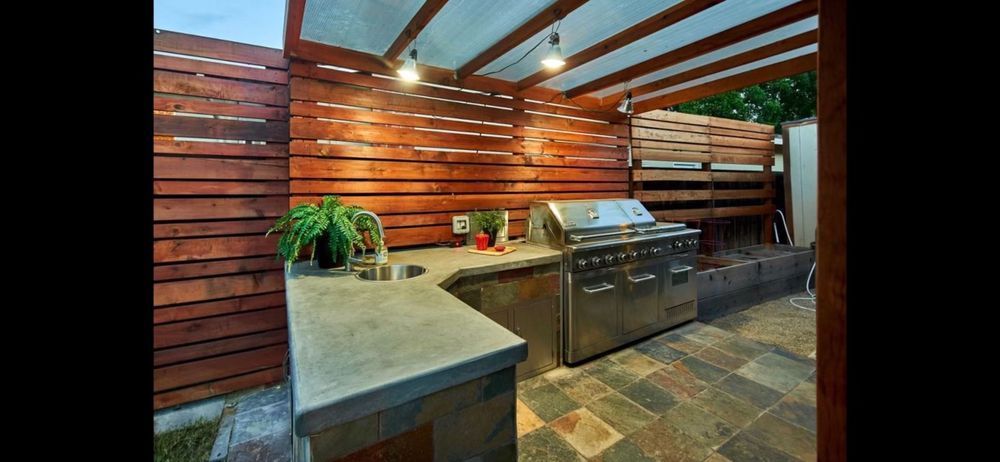 A kitchen with a grill , sink , and wooden fence.