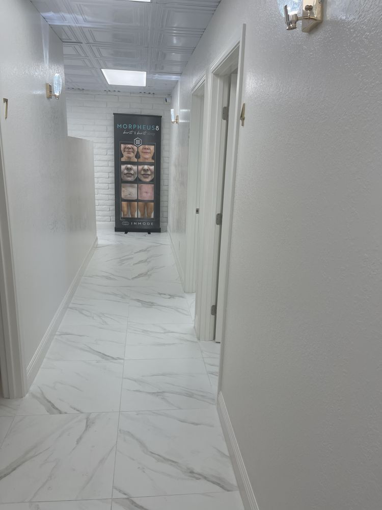 A long hallway with white tile floors and white walls in a building.