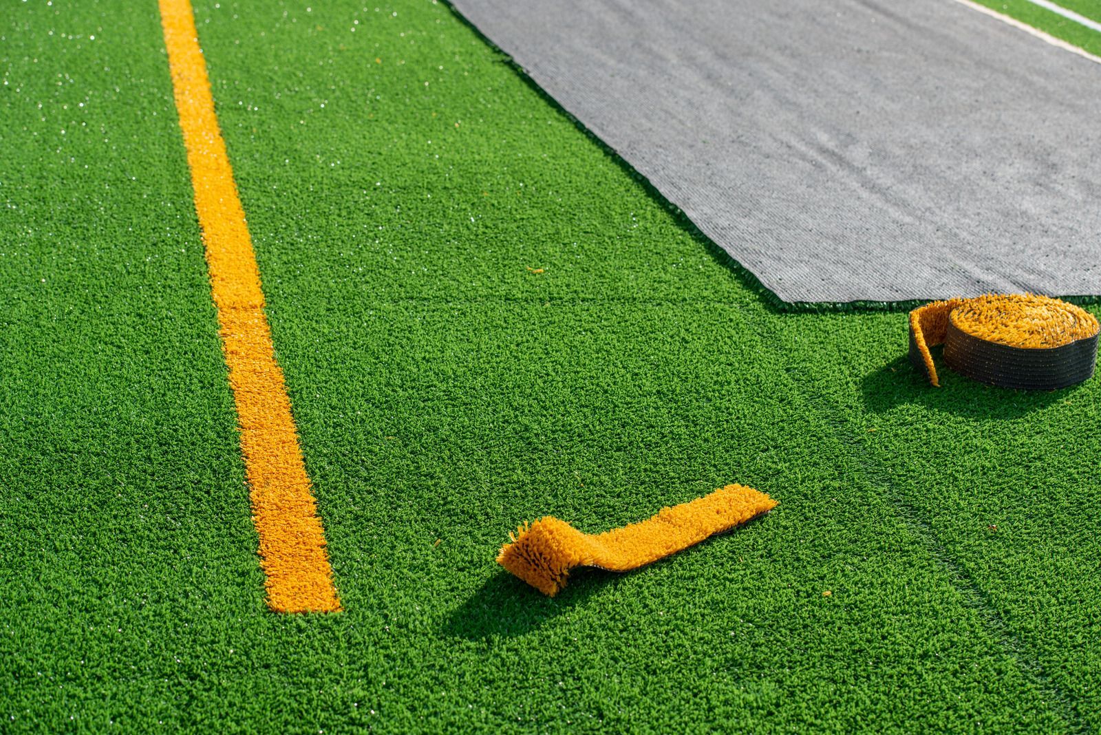 A yellow line is being painted on a soccer field.