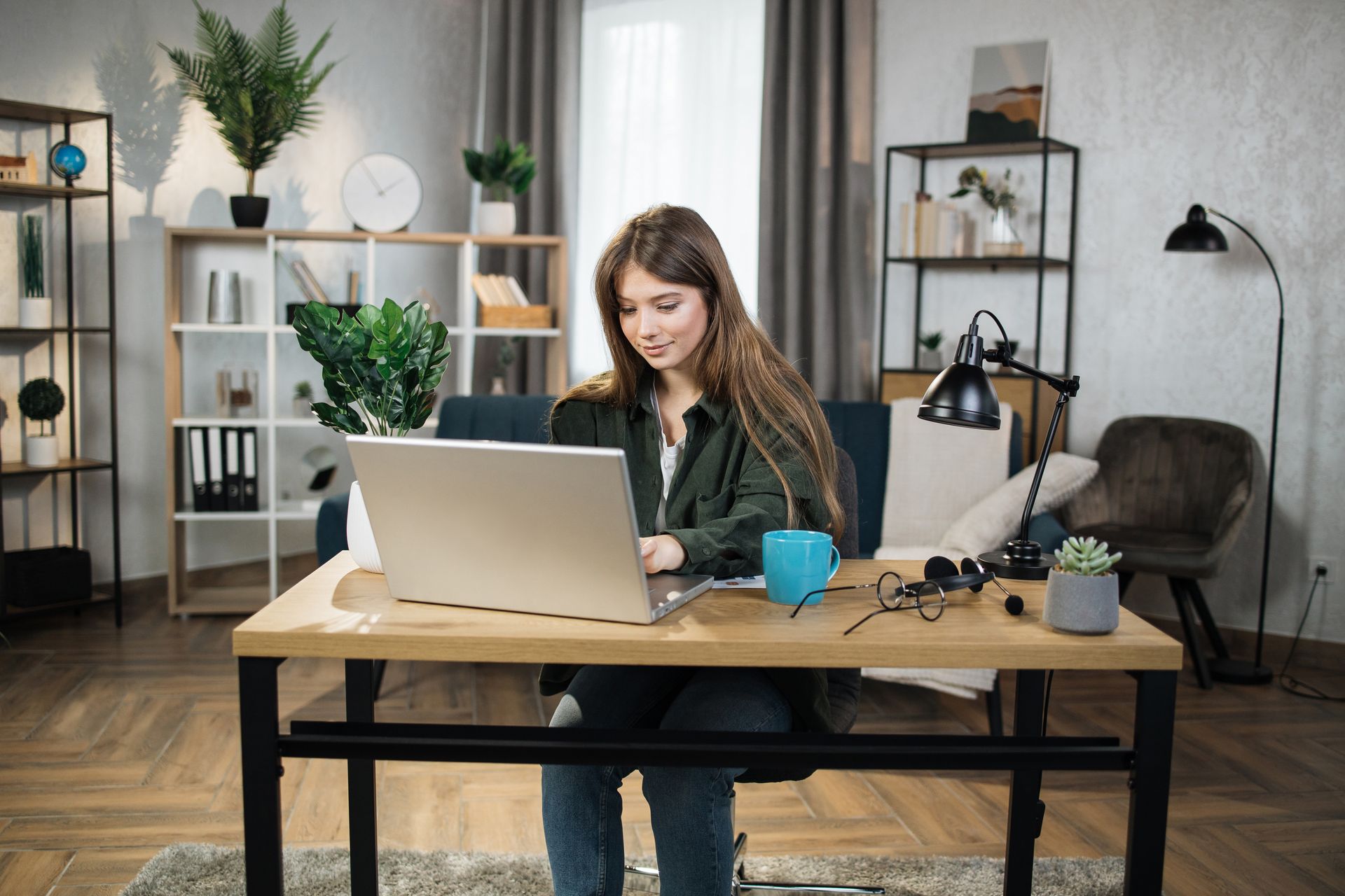 A woman is sitting at a desk using a laptop computer.