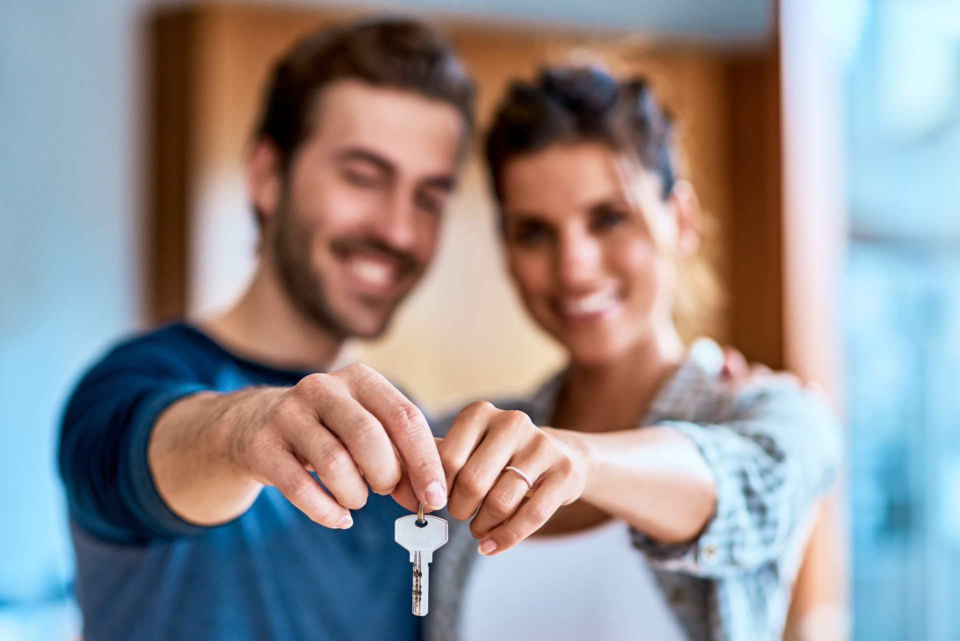 A man and a woman are holding a key to their new home.