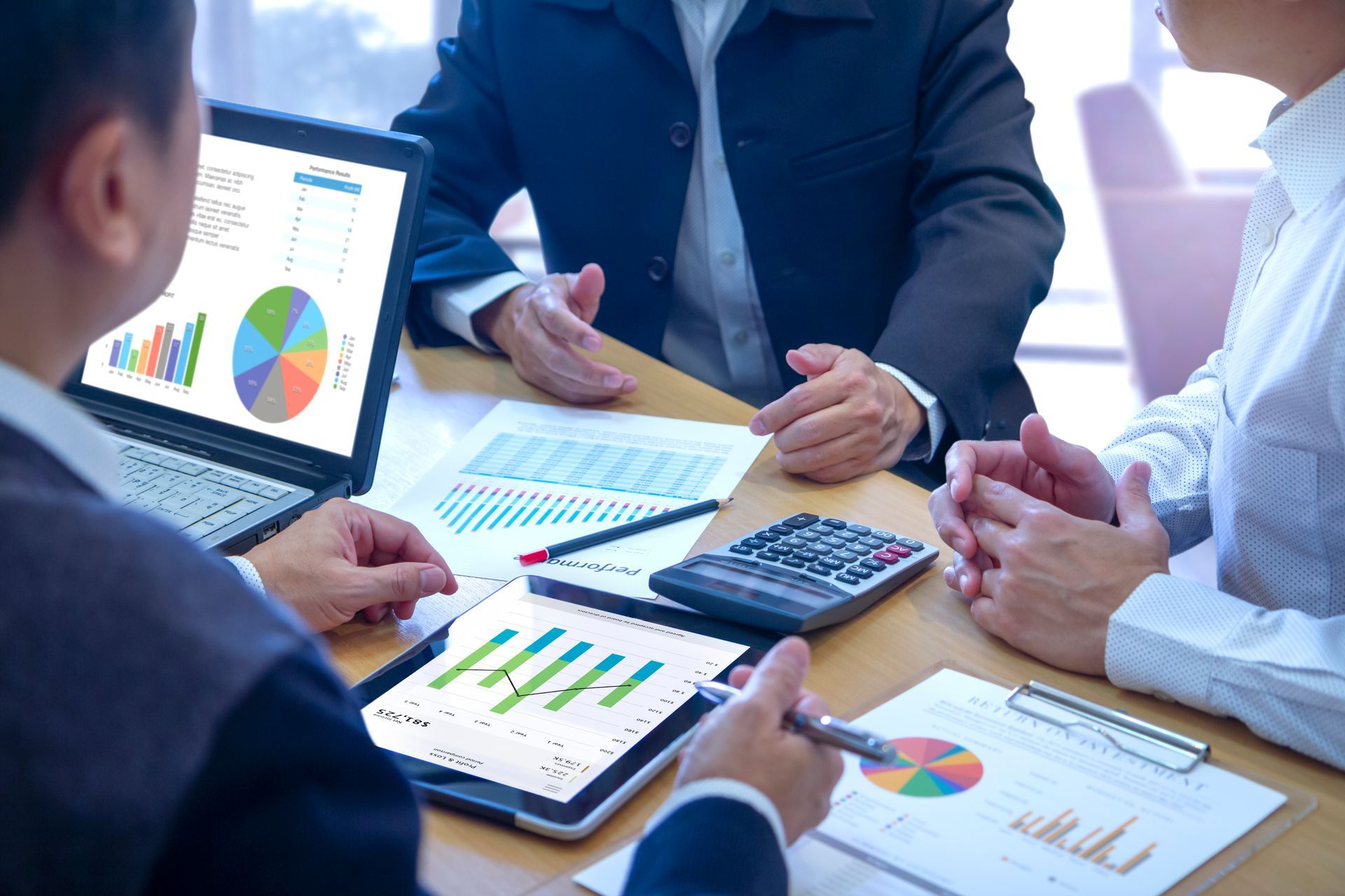 A group of people are sitting around a table looking at charts and graphs.