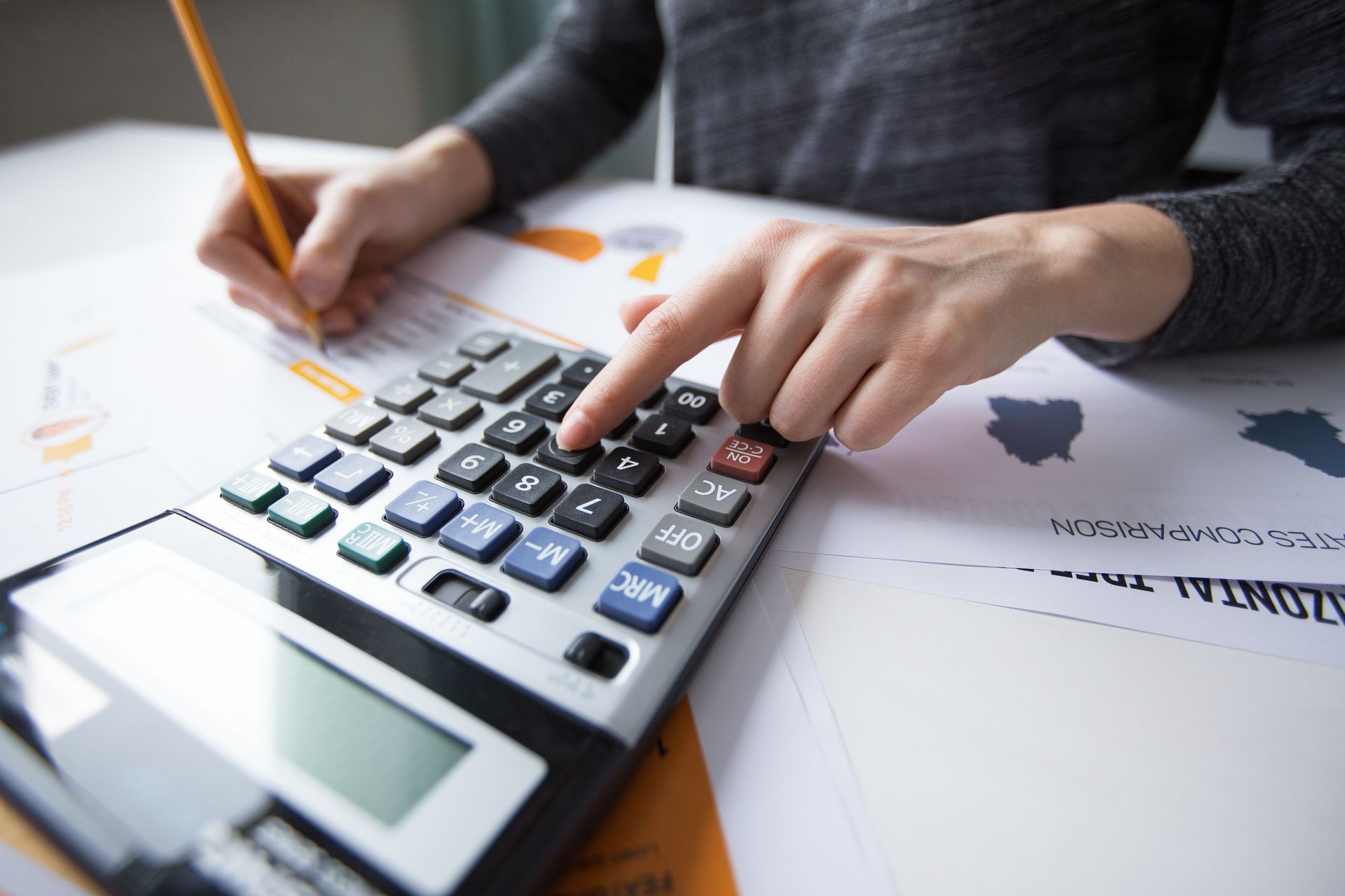 A person is using a calculator and writing on a piece of paper.