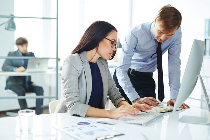 a man and a woman are looking at a computer screen .