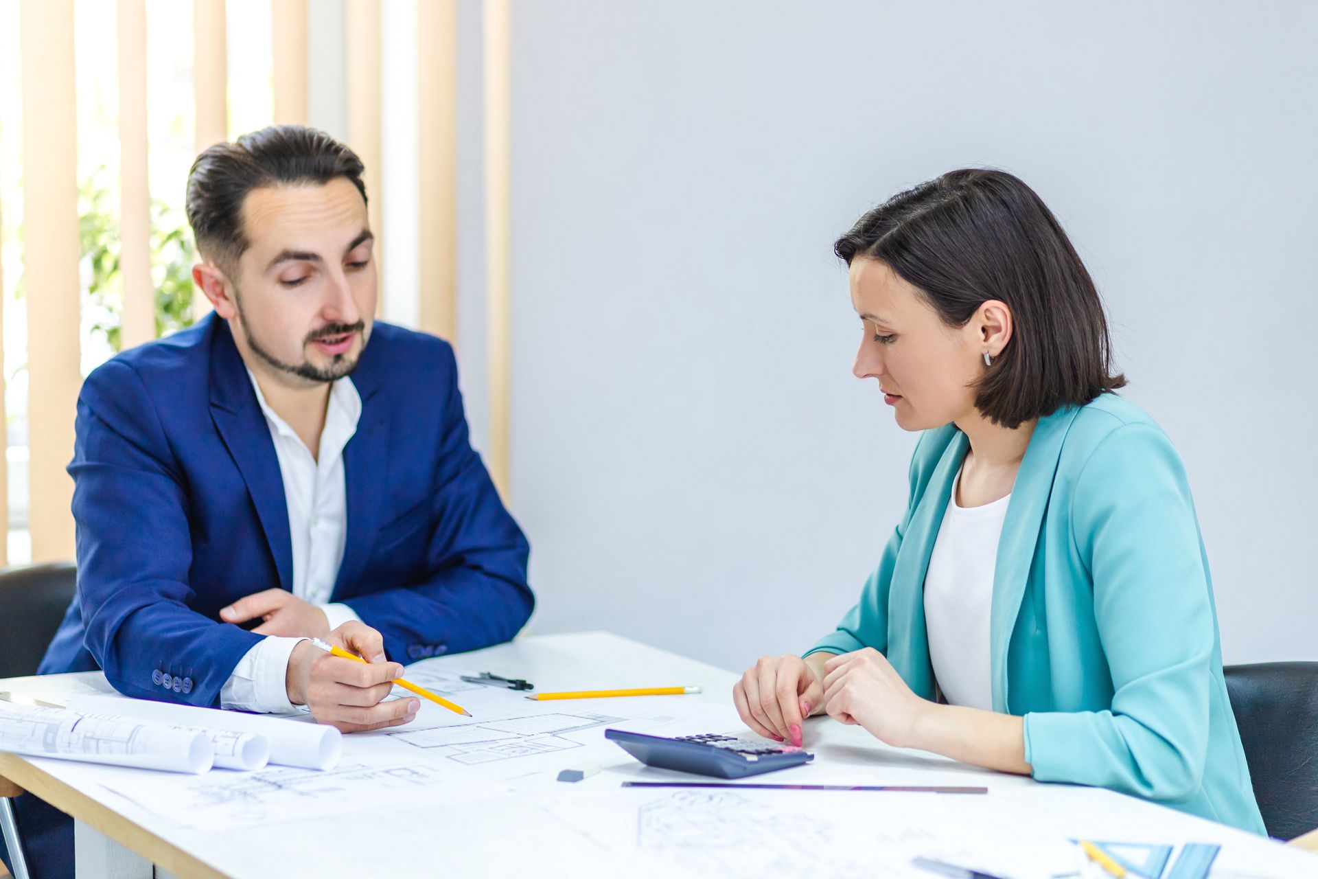 a man and a woman are sitting at a table looking at a blueprint .