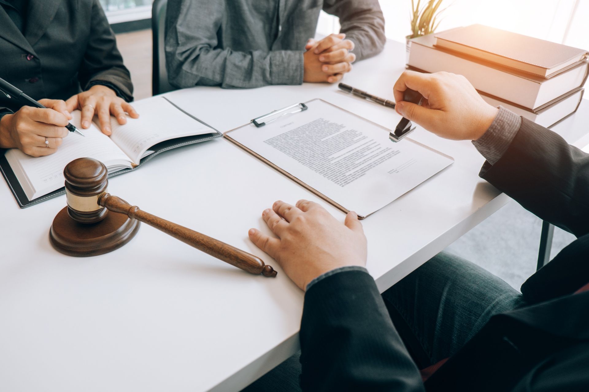 Business meeting with documents and gavel on a white table, people discussing a contract