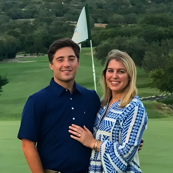 A man and a woman are posing for a picture on a golf course