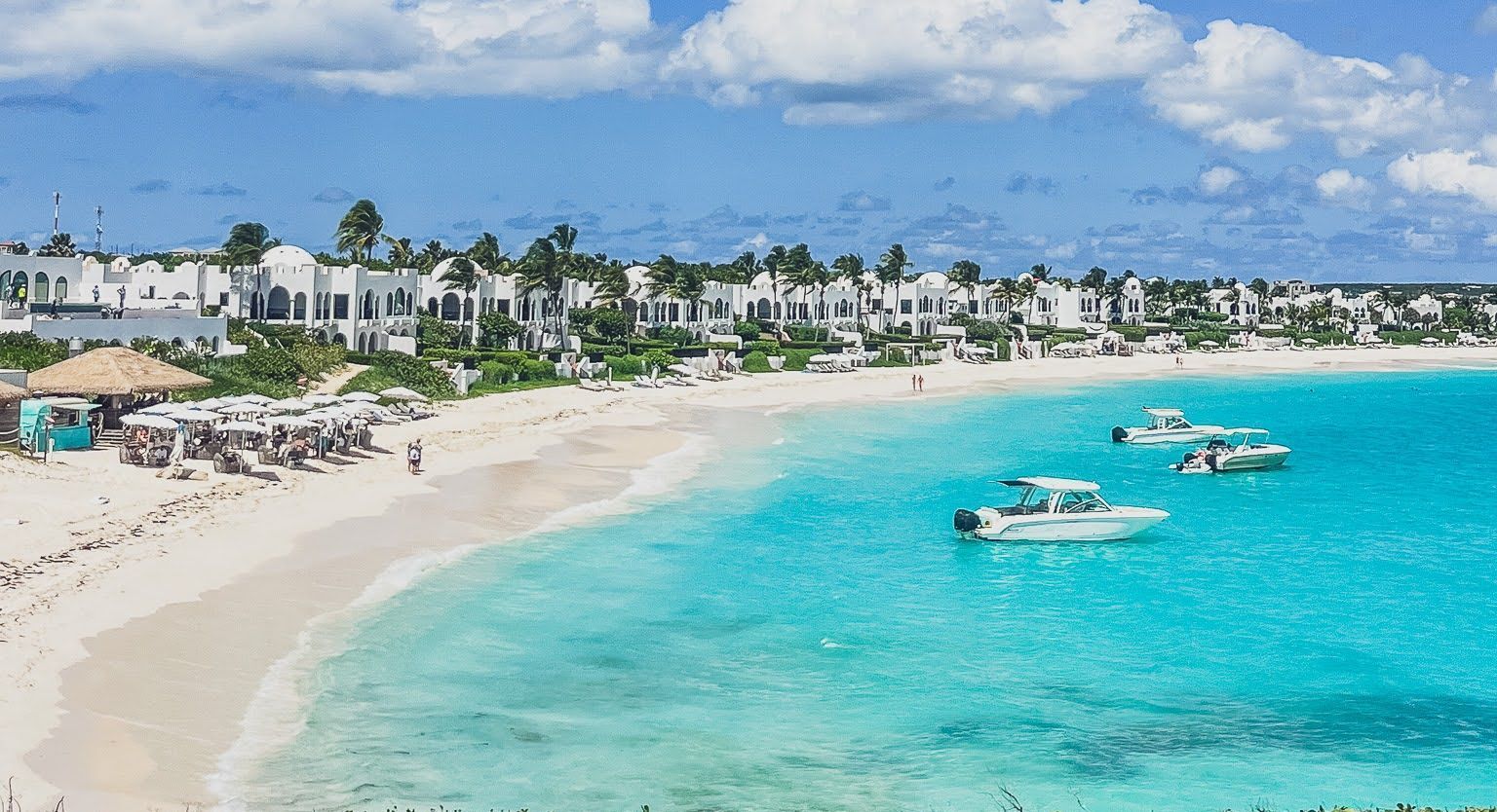 A beach with boats in the water and a blue sky