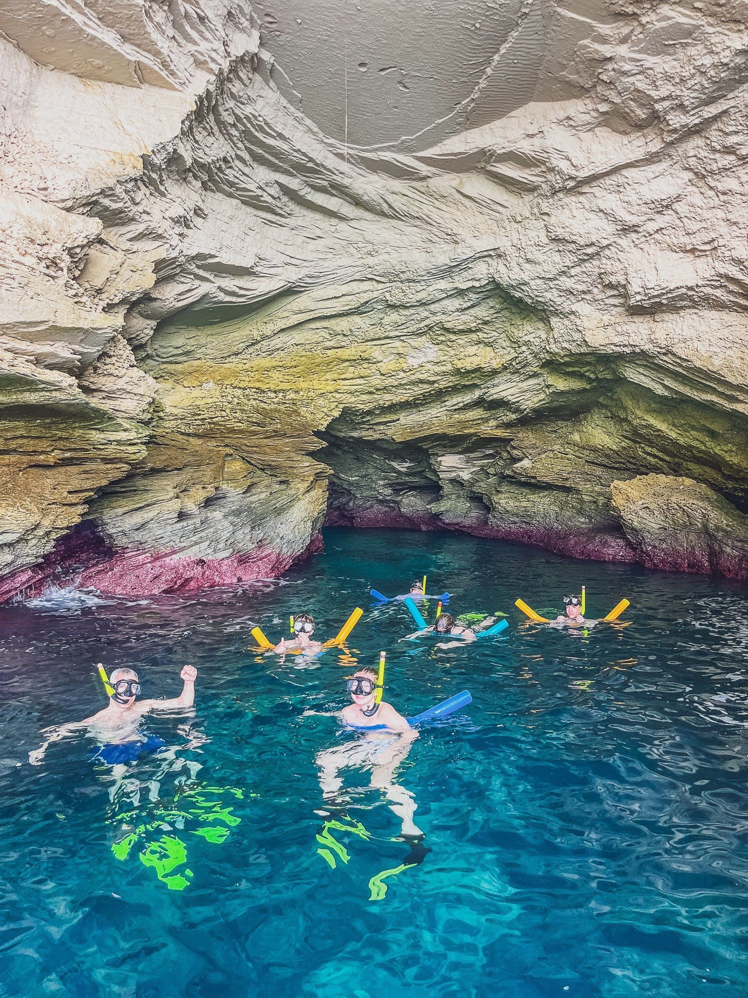A group of people are swimming in a cave in the ocean.