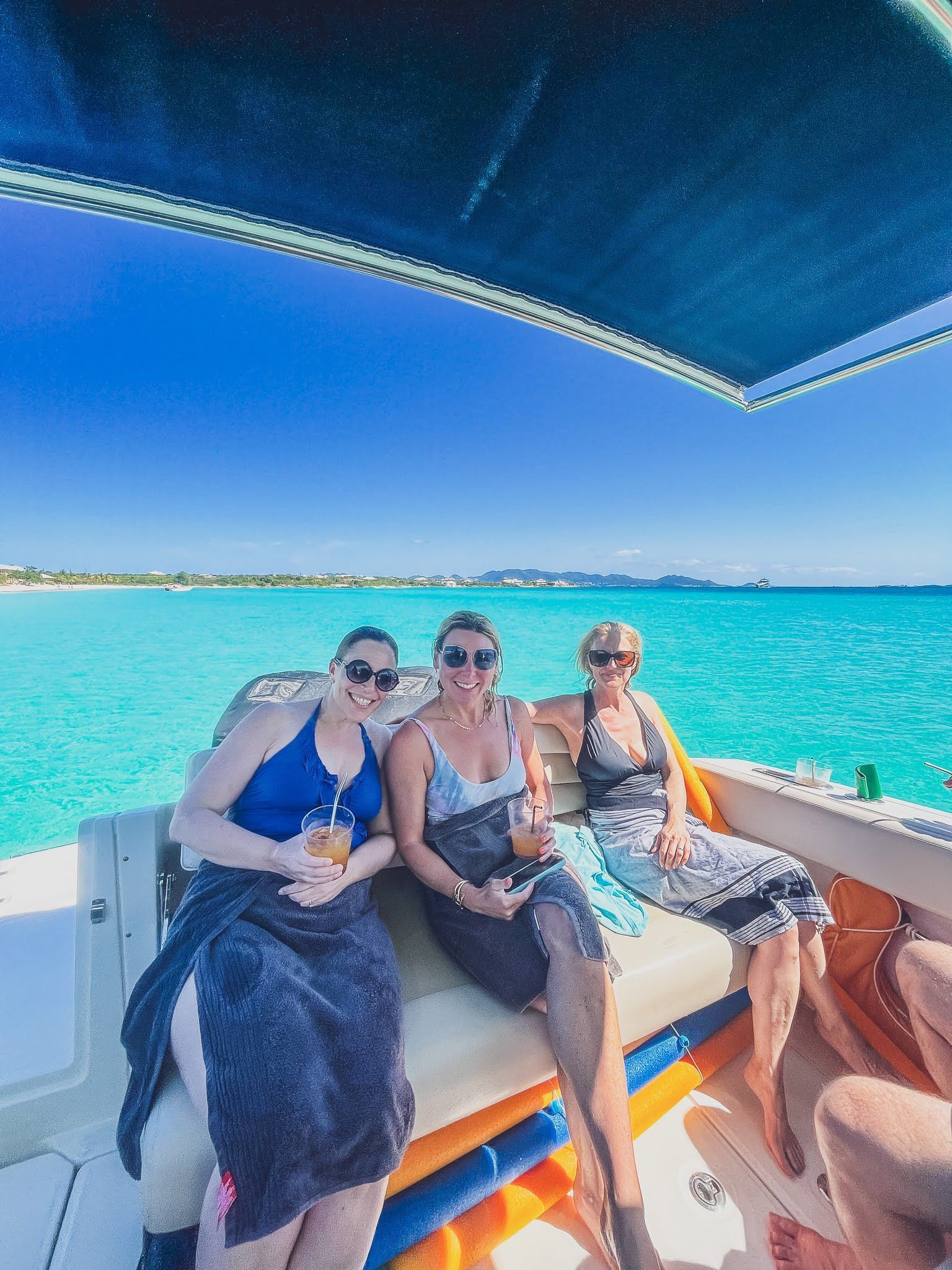 Three women are sitting on a boat in the ocean.