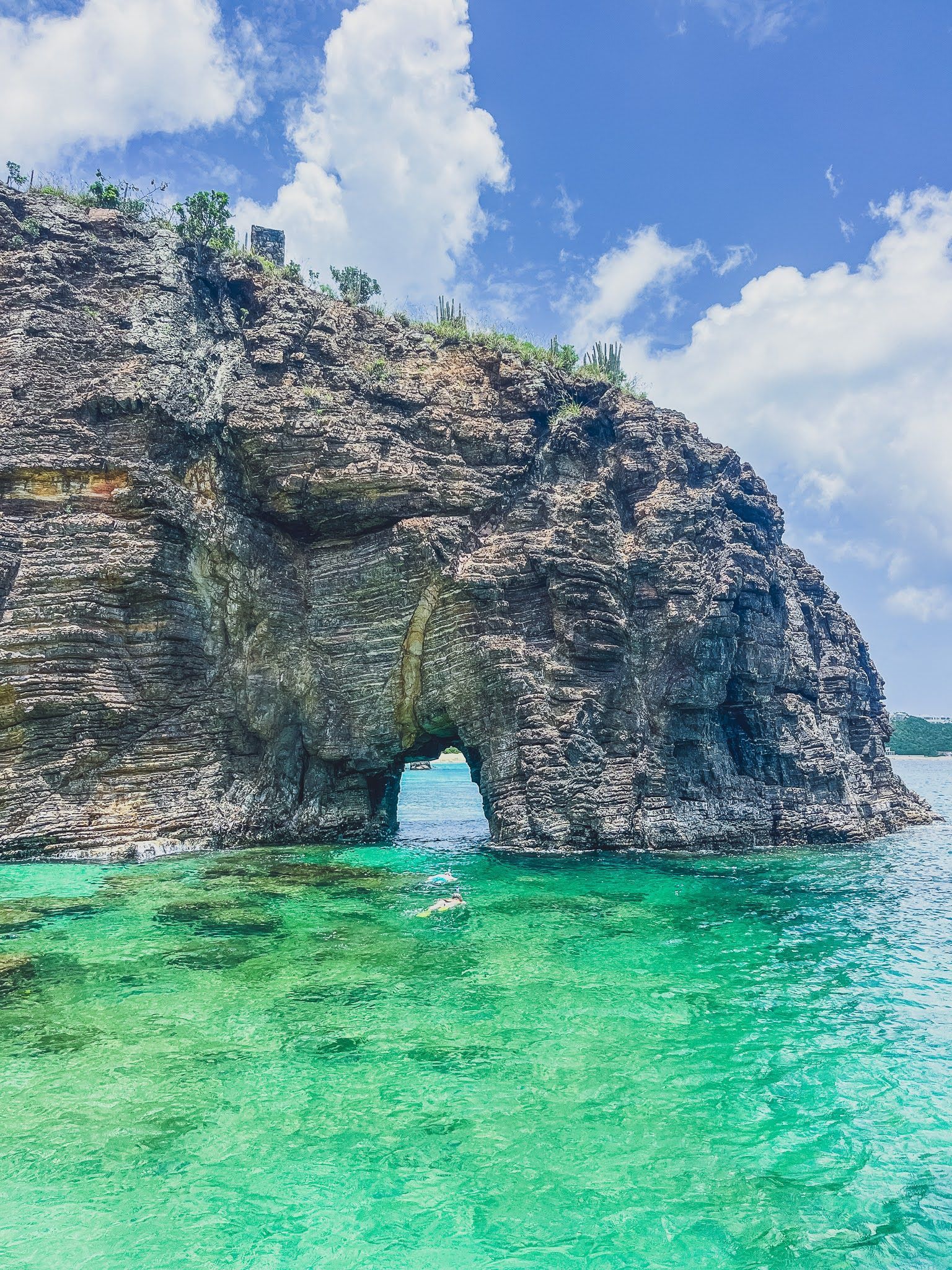 There is a large rock formation in the middle of the ocean.