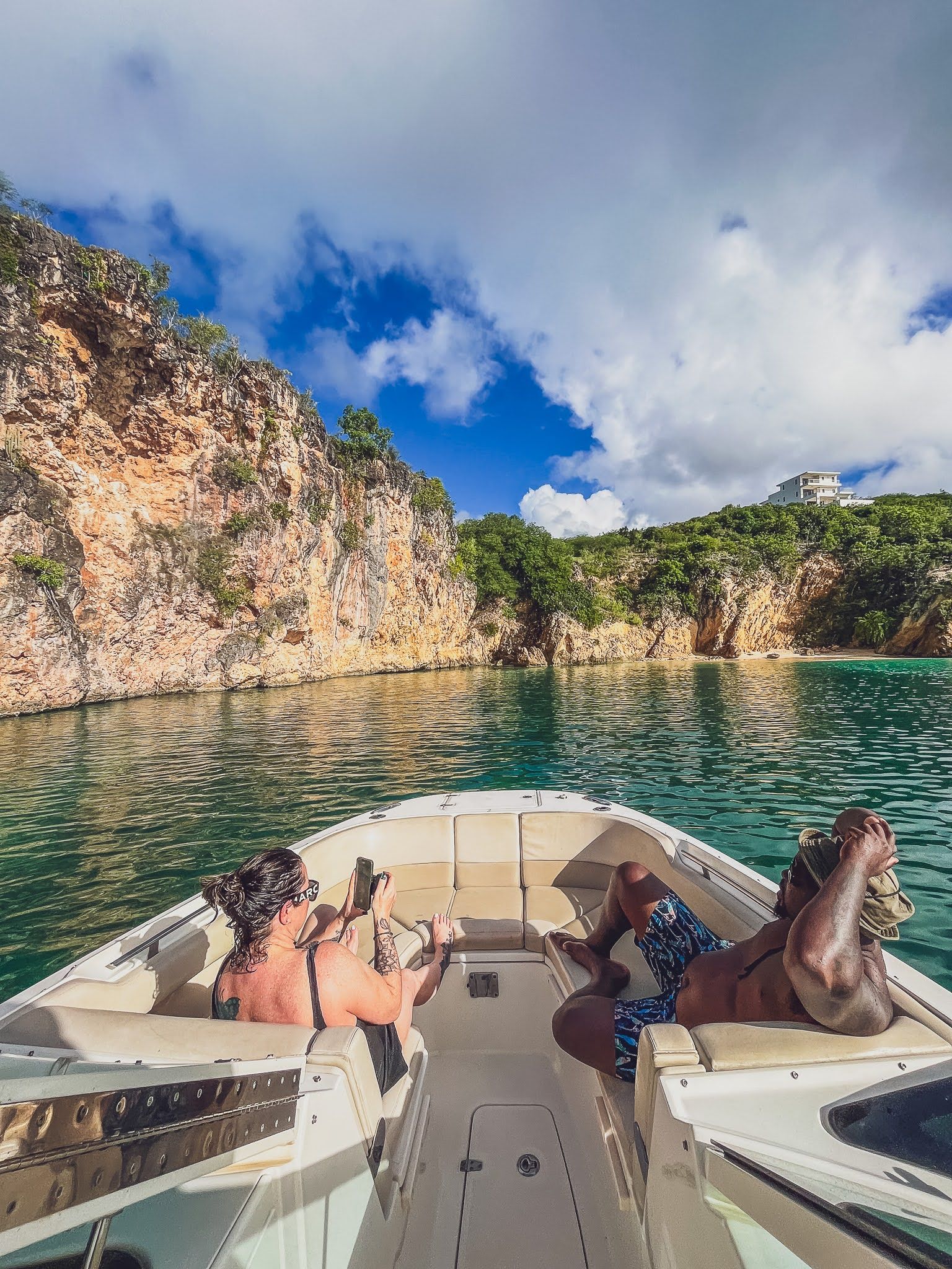 Two people are laying on the back of a boat in the water.