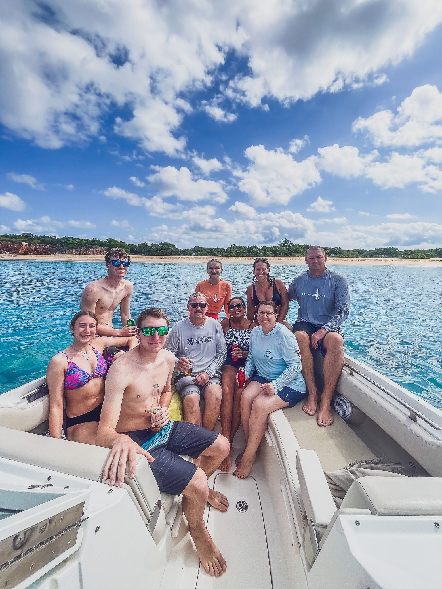 A group of people are sitting on the back of a boat in the ocean.