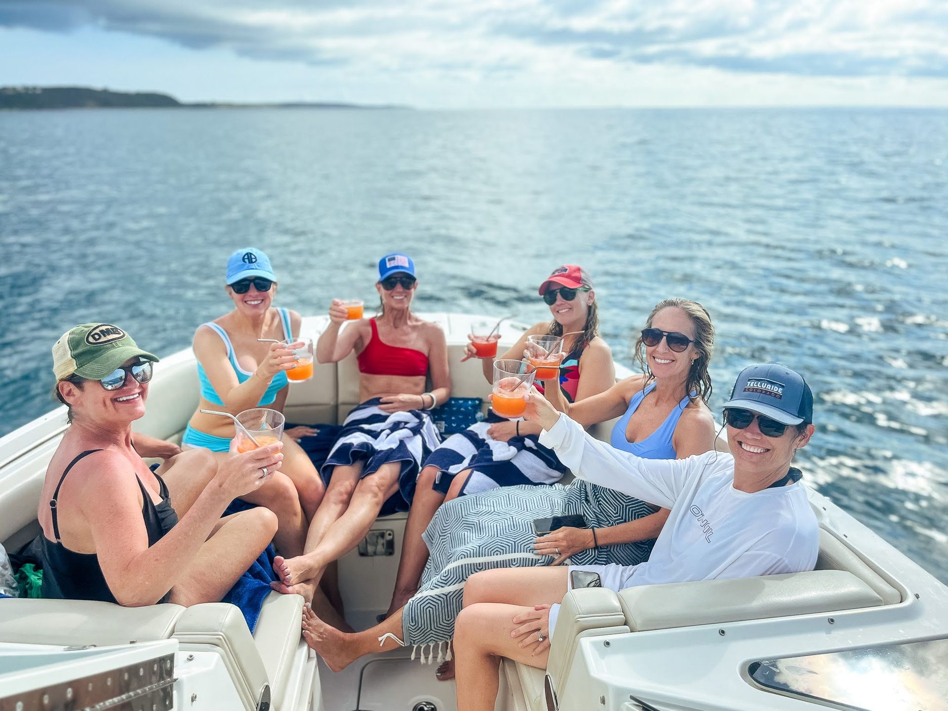 A group of people are sitting on a boat toasting with drinks.