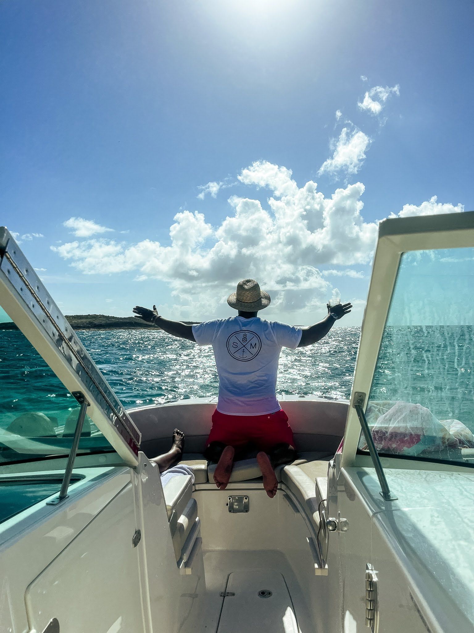 A man is sitting on the back of a boat with his arms outstretched.