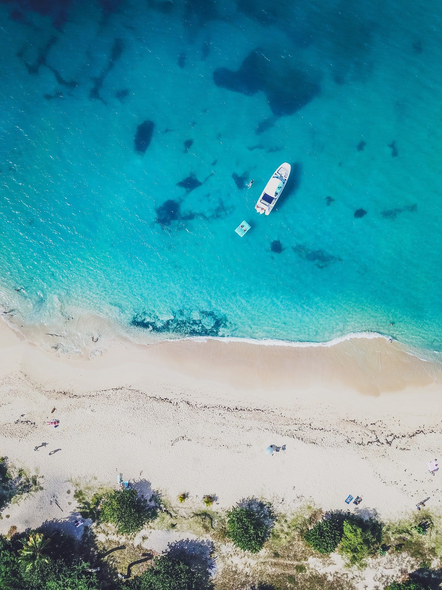 An aerial view of a beach with a boat in the water.