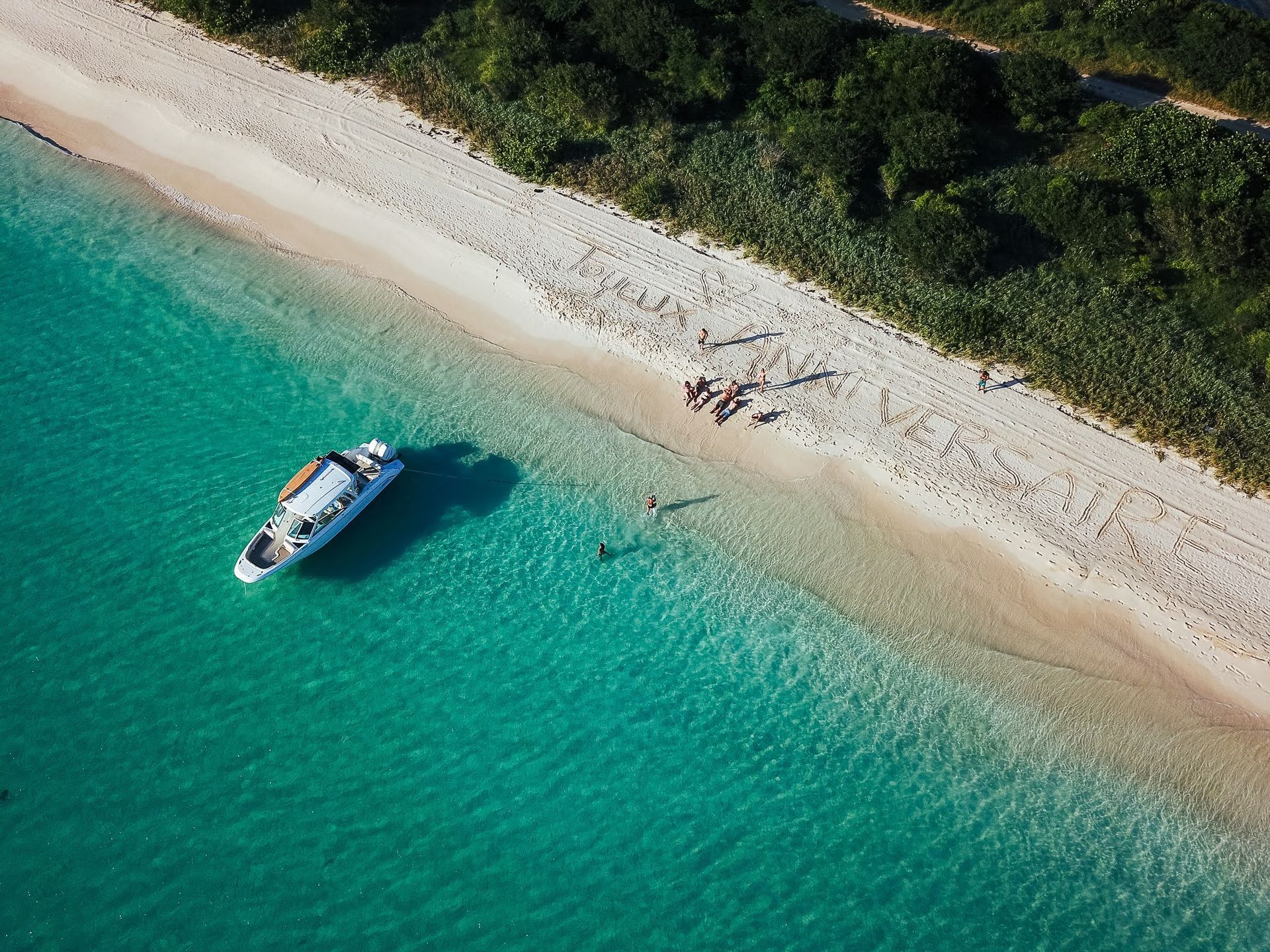 An aerial view of a beach with a boat in the water.