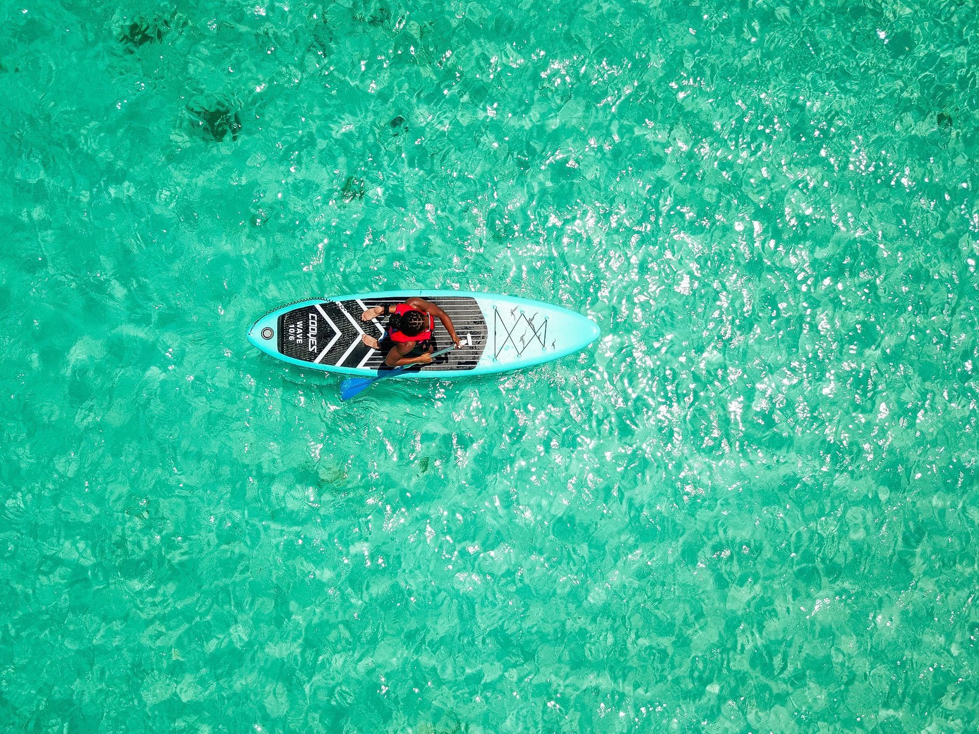 An aerial view of a person on a paddle board in the ocean.