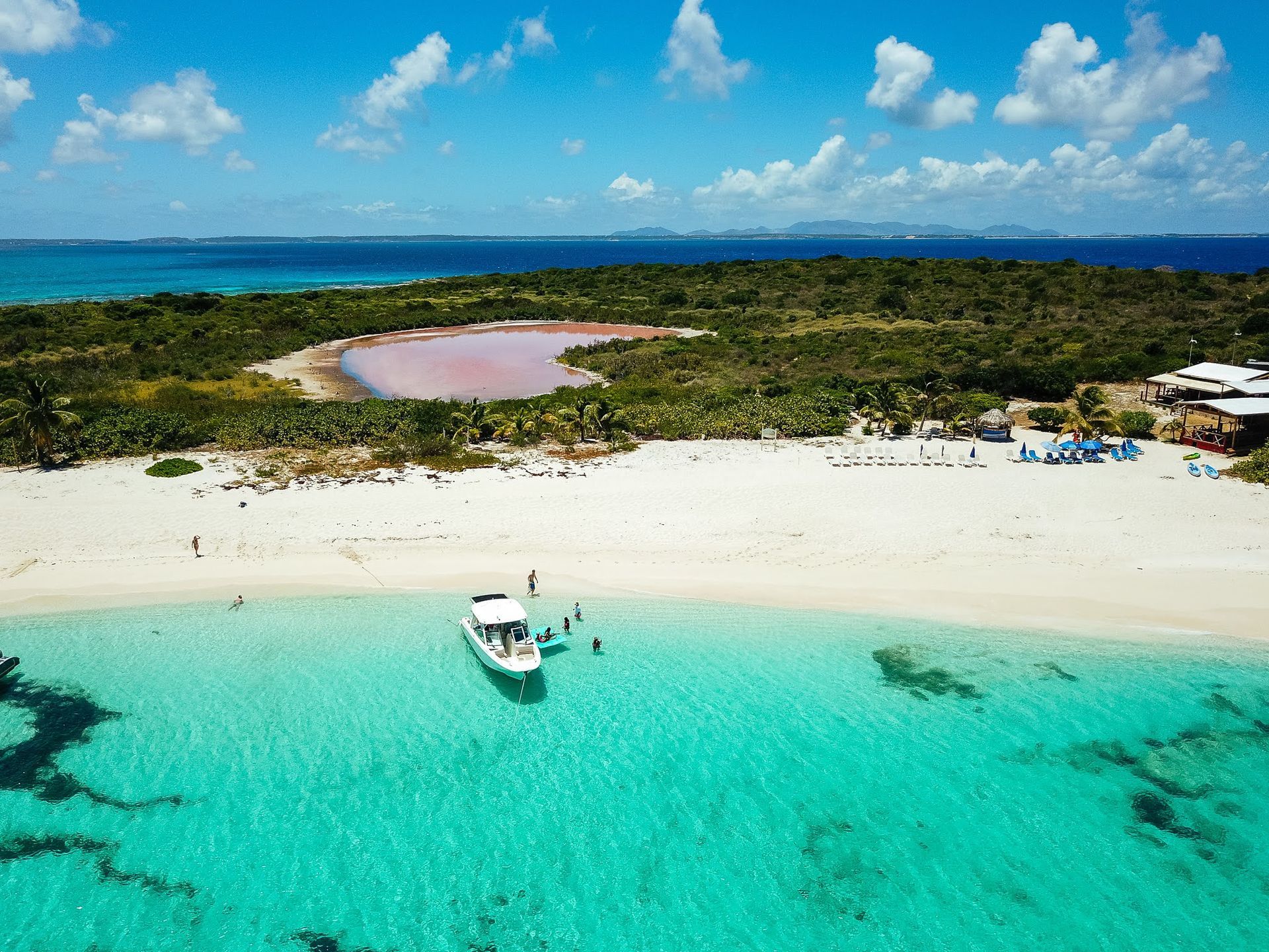 An aerial view of a beach with a boat in the water.