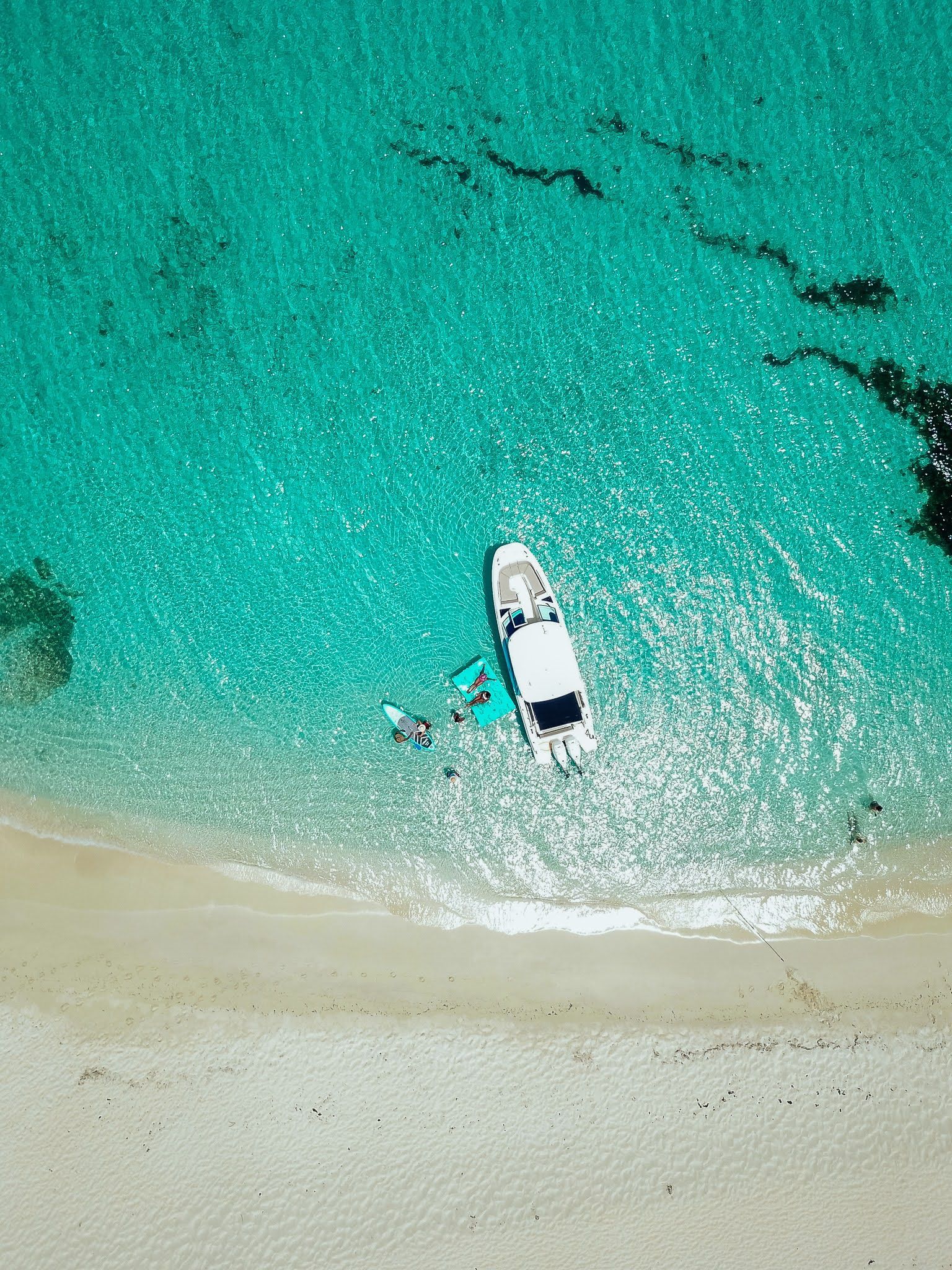An aerial view of a boat in the ocean near a beach.