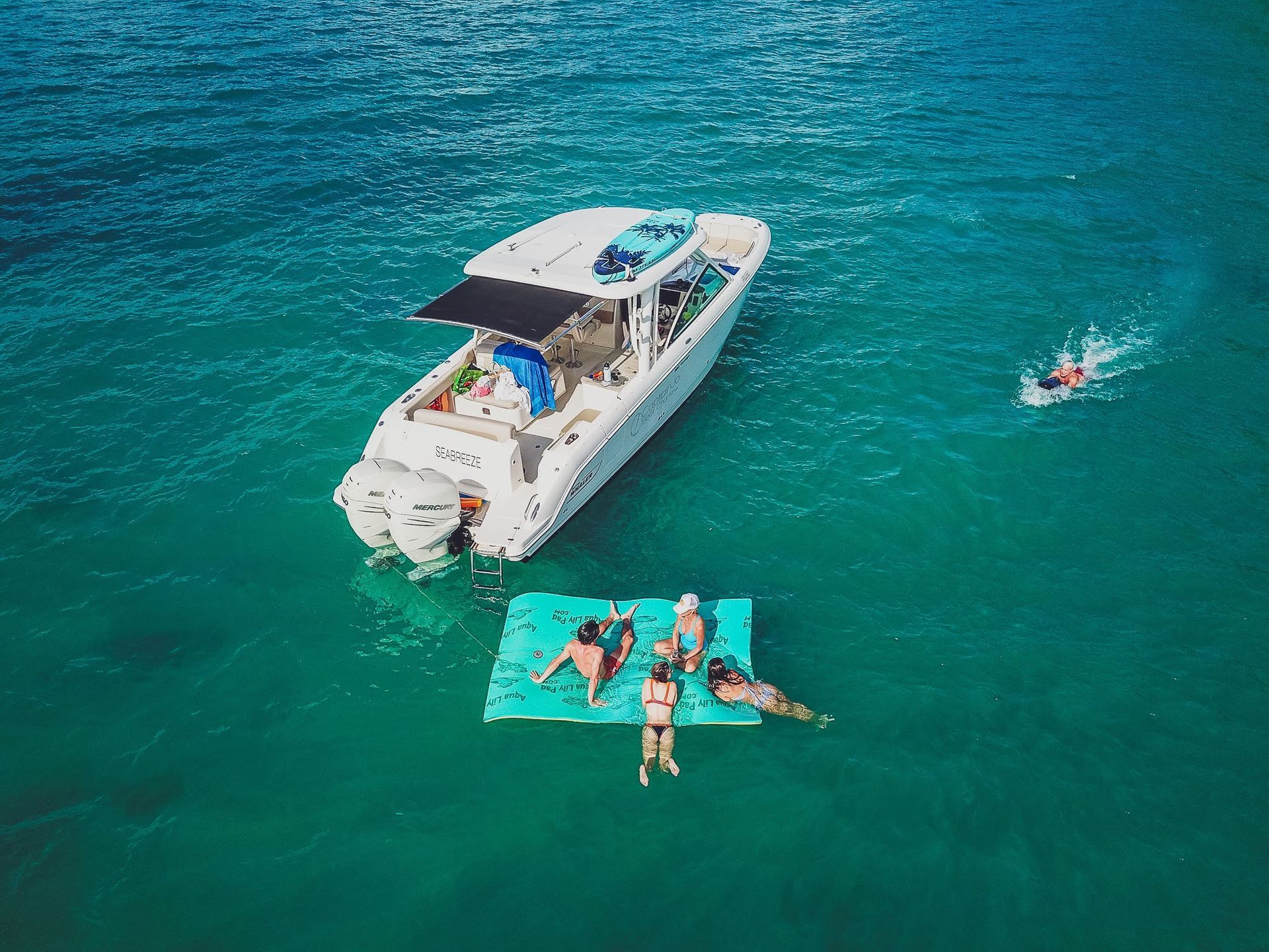 A group of people are floating on a raft in the ocean next to a boat.