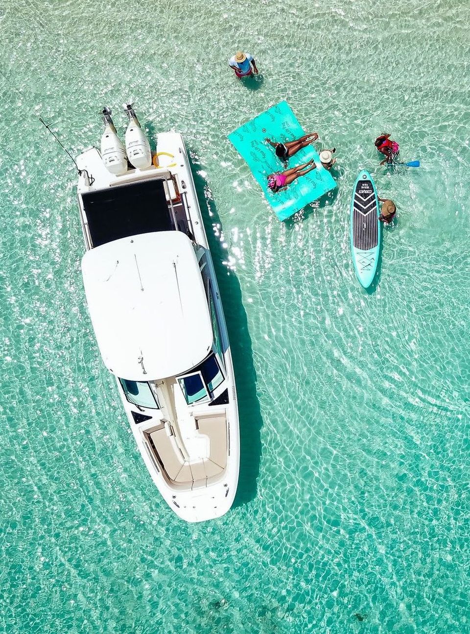 An aerial view of a boat and people floating on rafts in the ocean.