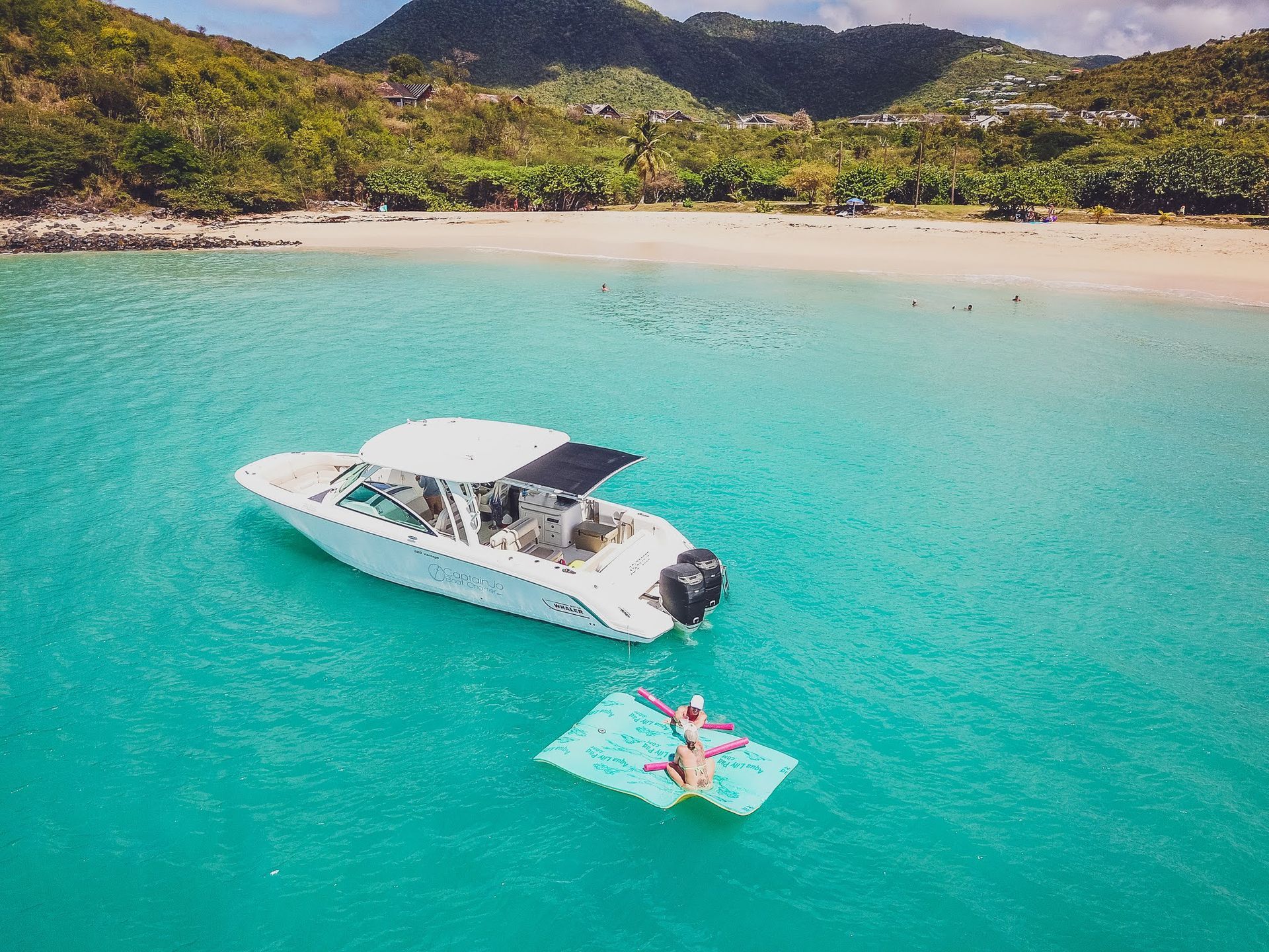 A woman is floating on a raft next to a boat in the ocean.