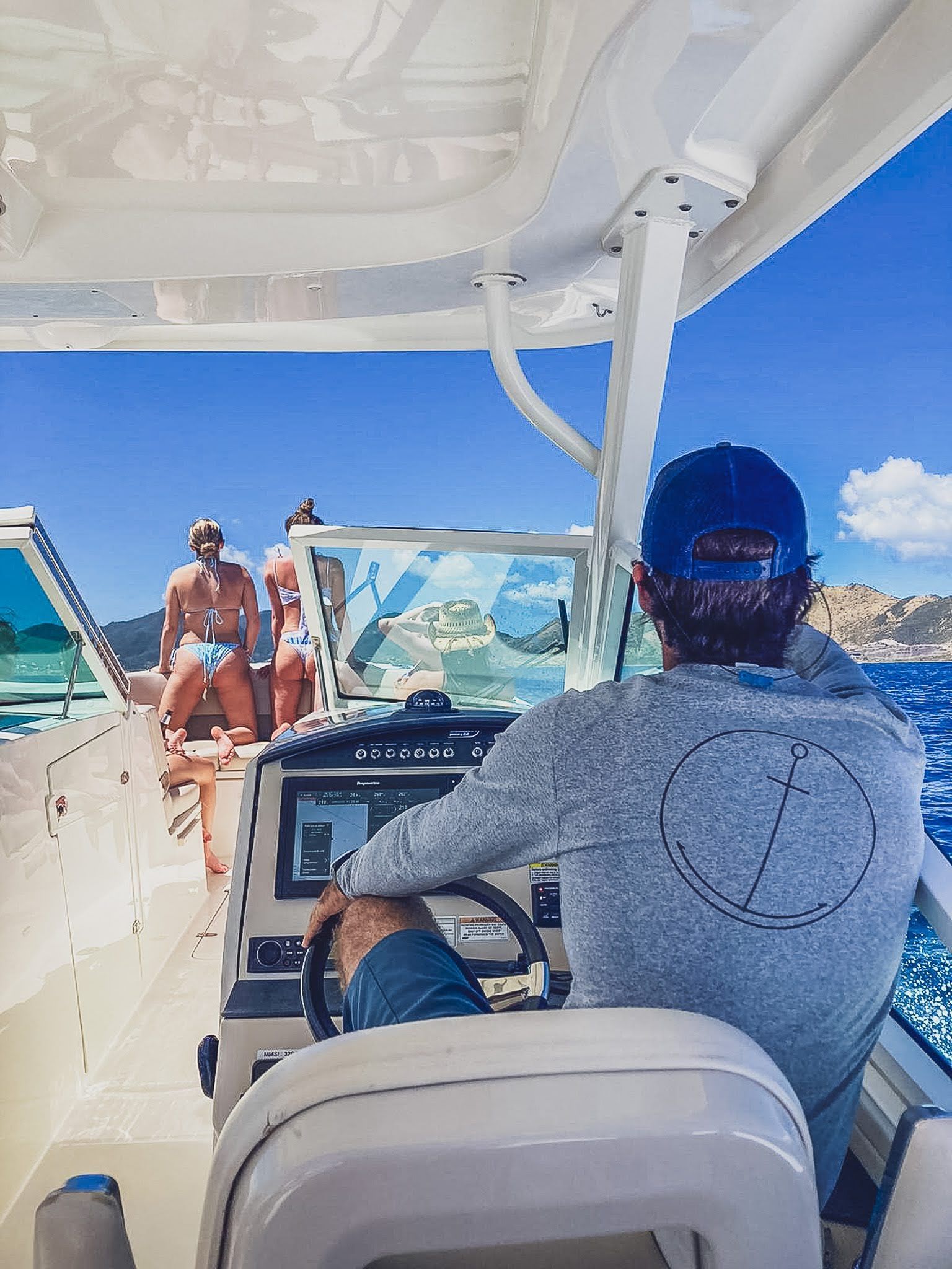 A man is driving a boat with a group of people on it.