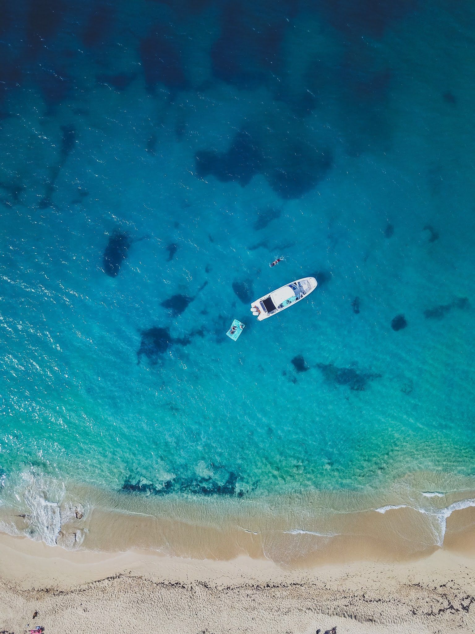 An aerial view of a beach with a boat in the water.