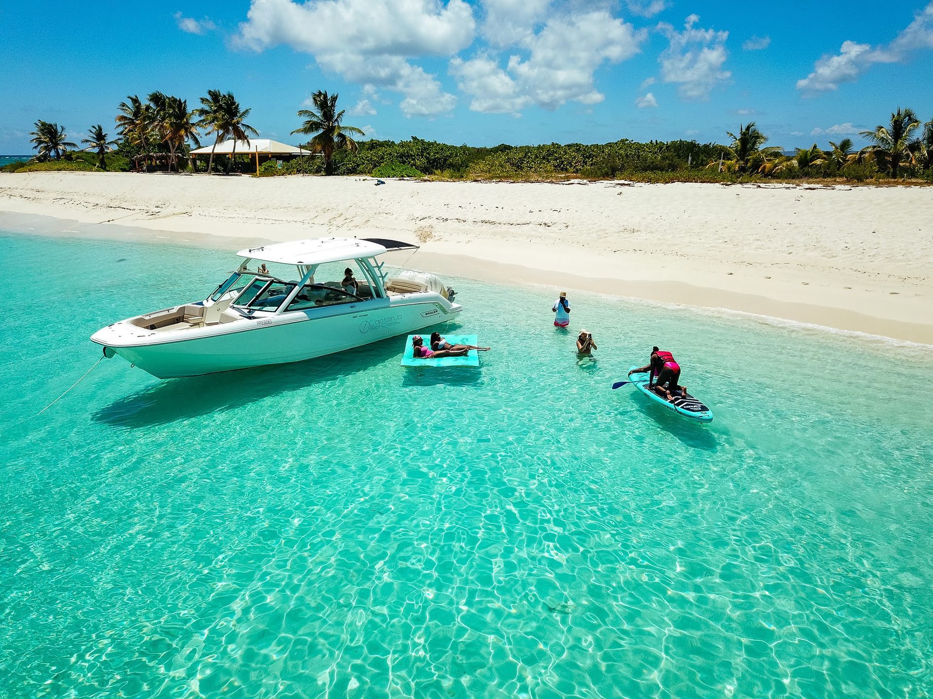 An aerial view of a beach with a boat and people in the water.