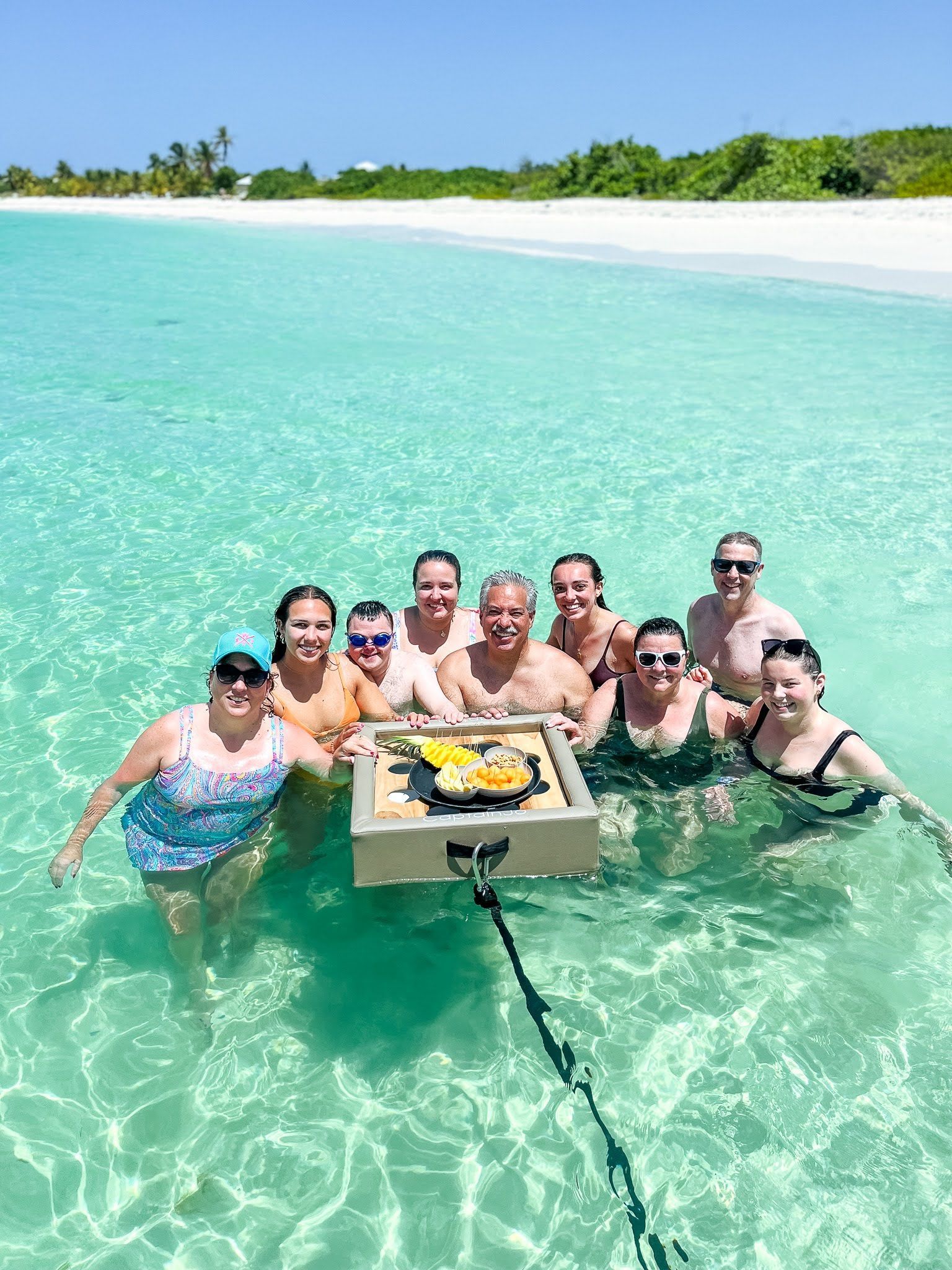 A group of people are standing in the water with a tray of food.