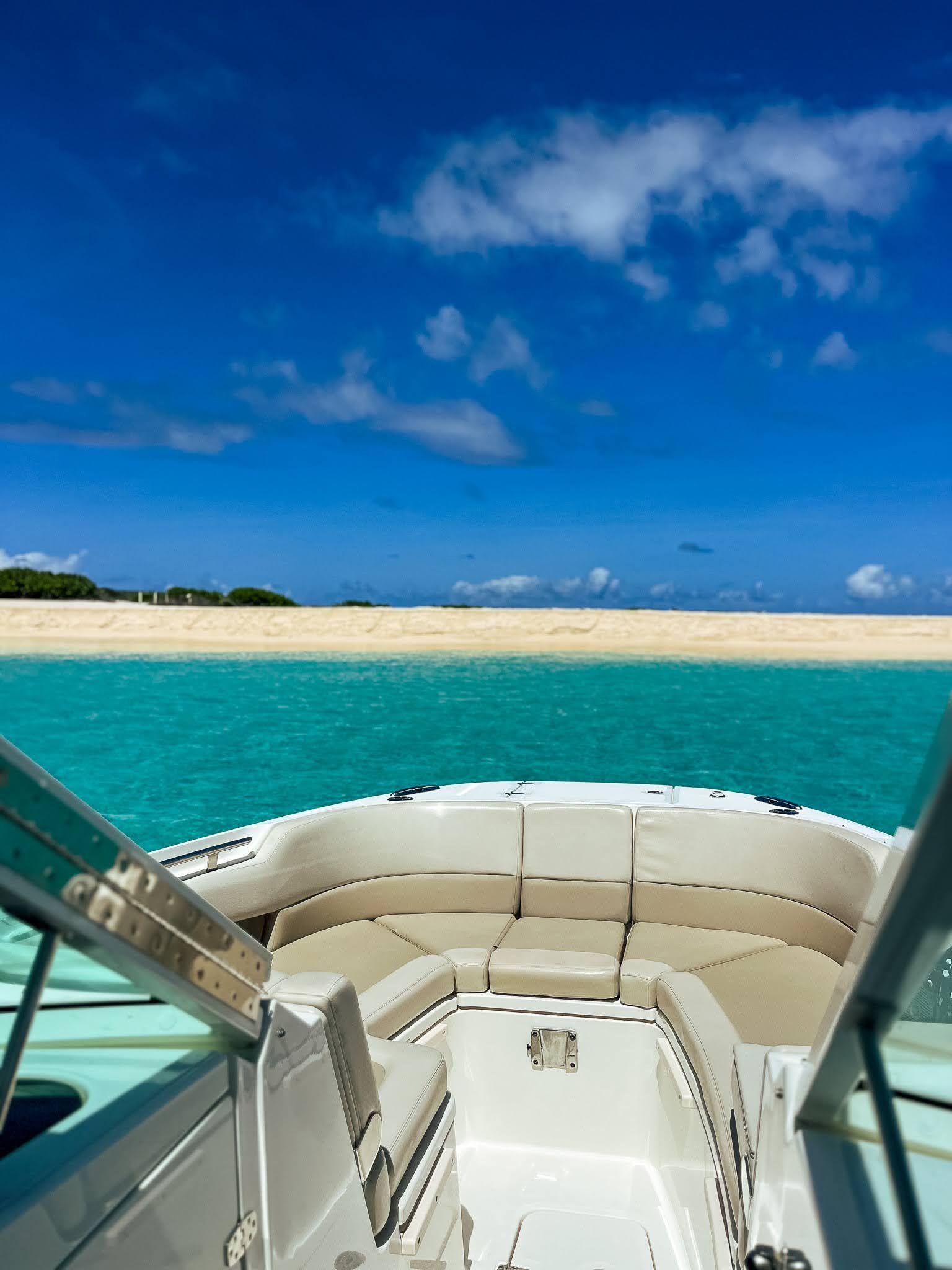 A boat is floating on top of a body of water with a sandy beach in the background.