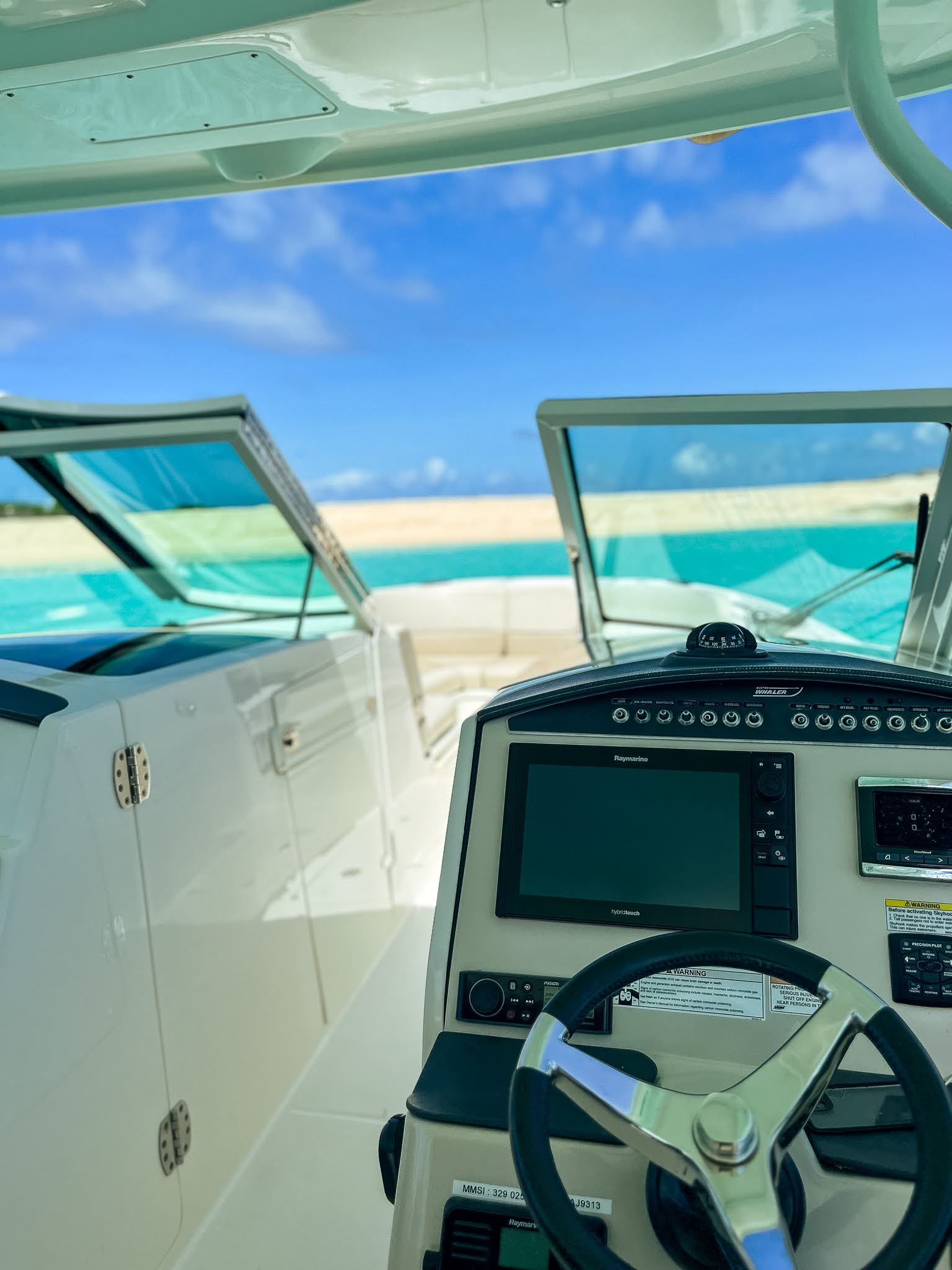 The inside of a boat with a steering wheel and a monitor