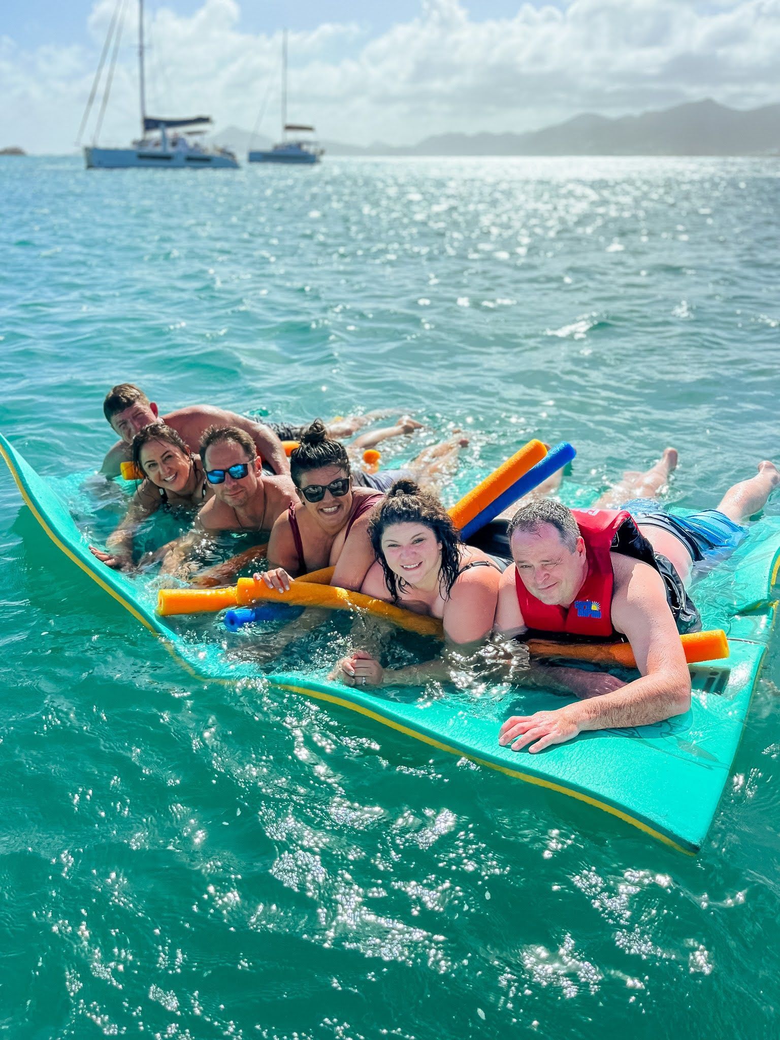 A group of people are laying on a raft in the water.
