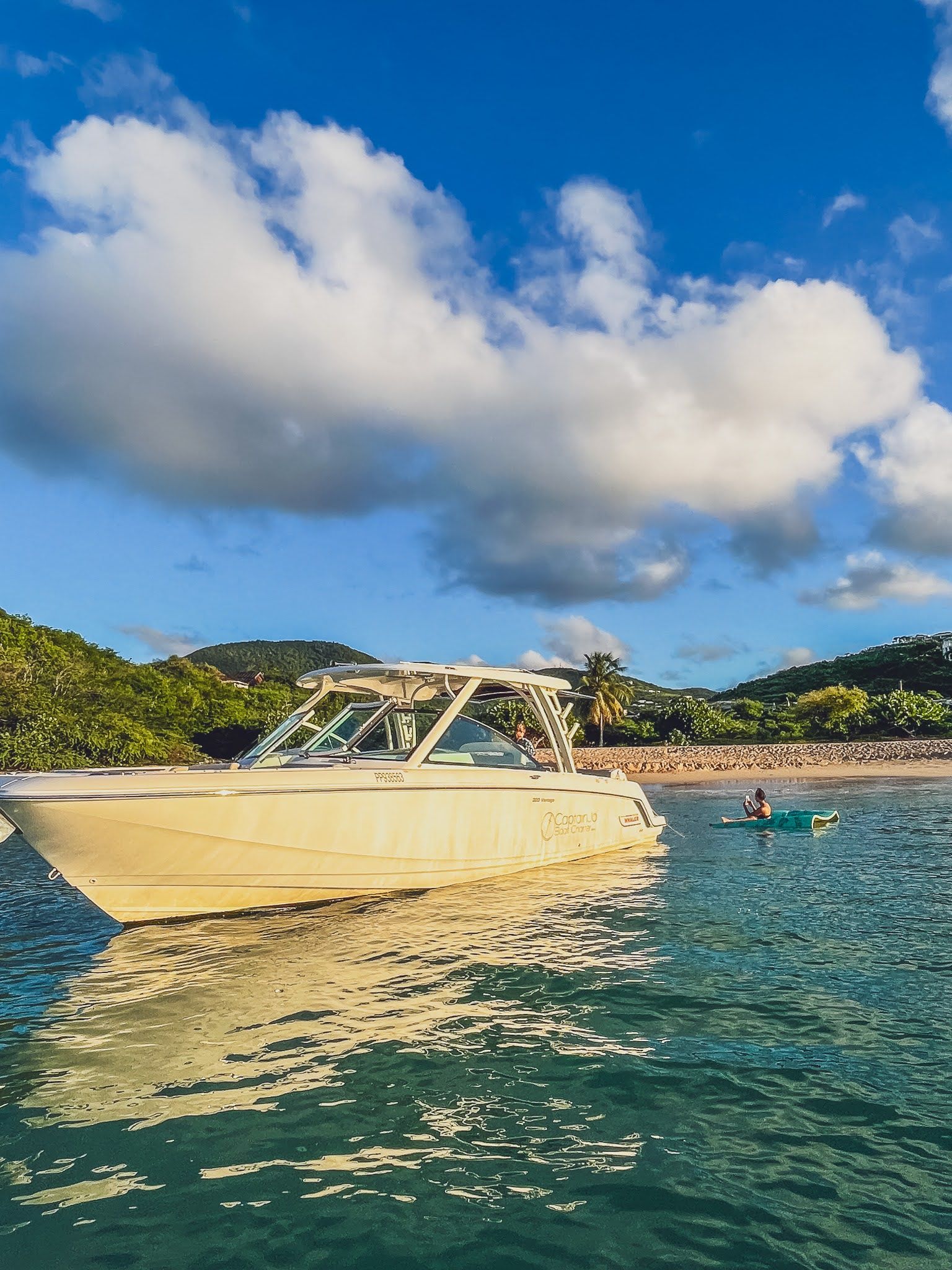 A boat is floating on top of a body of water near a beach.