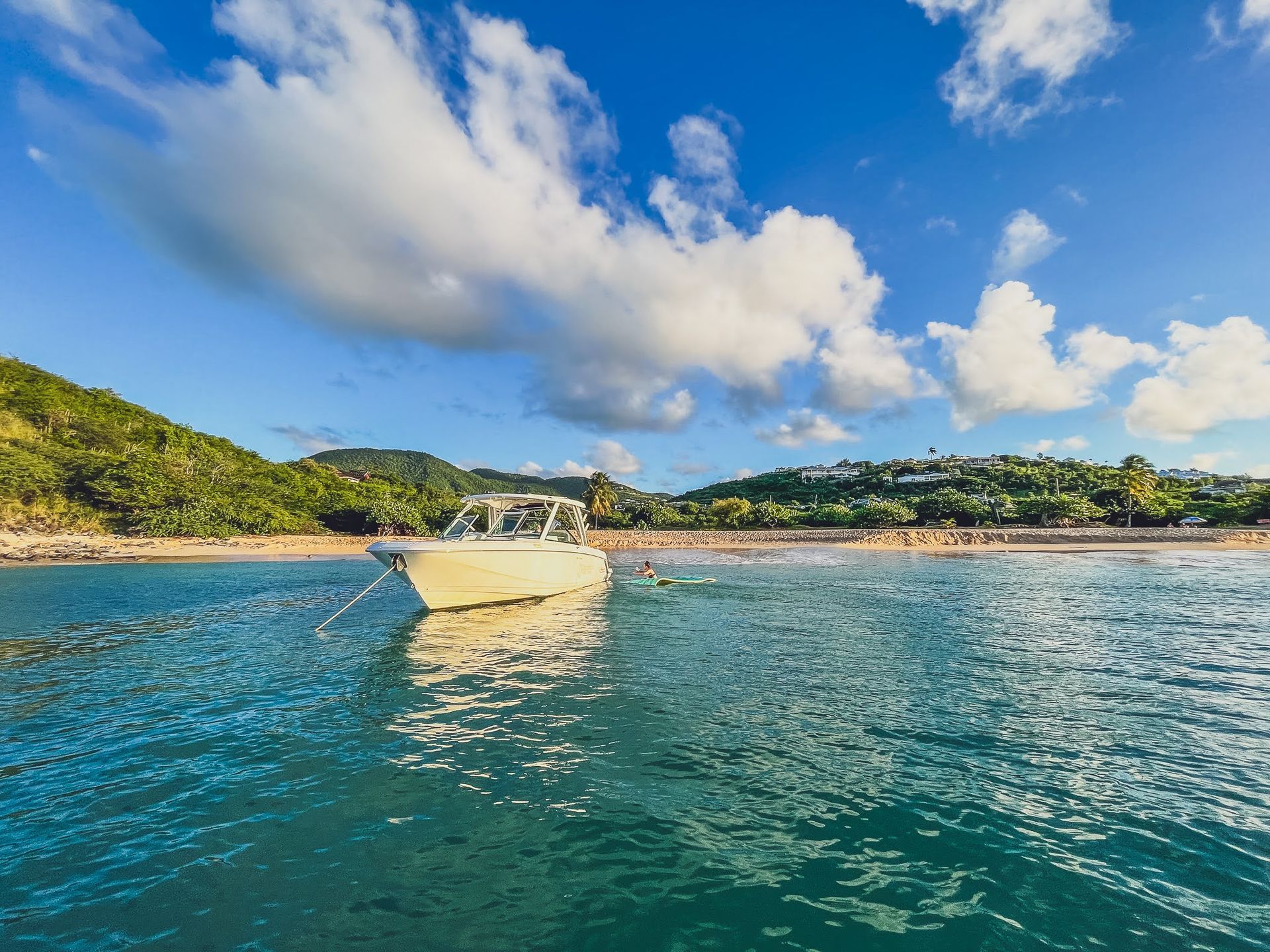 A boat is floating on top of a body of water near a beach.