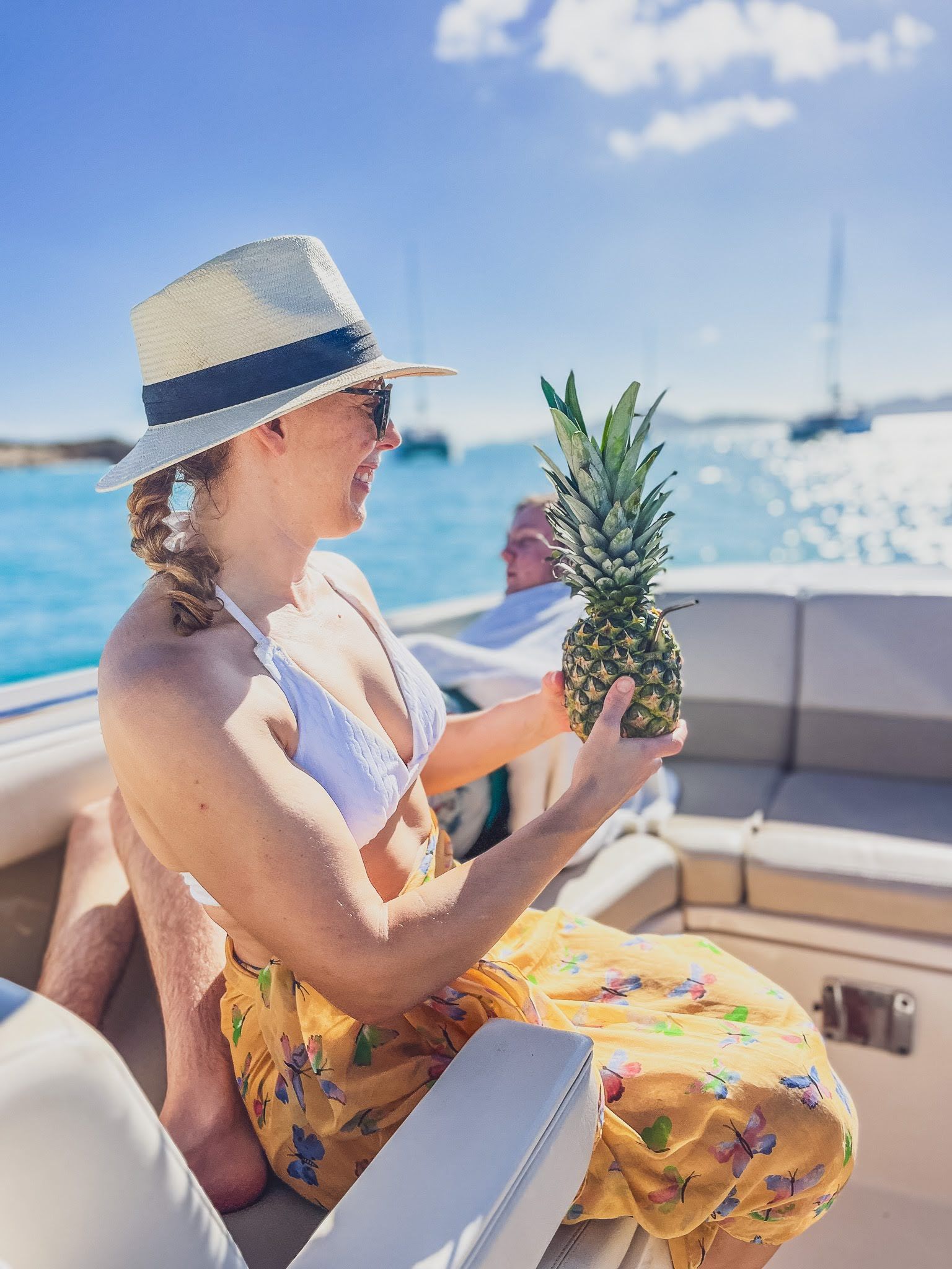A woman is sitting on a boat holding a pineapple.