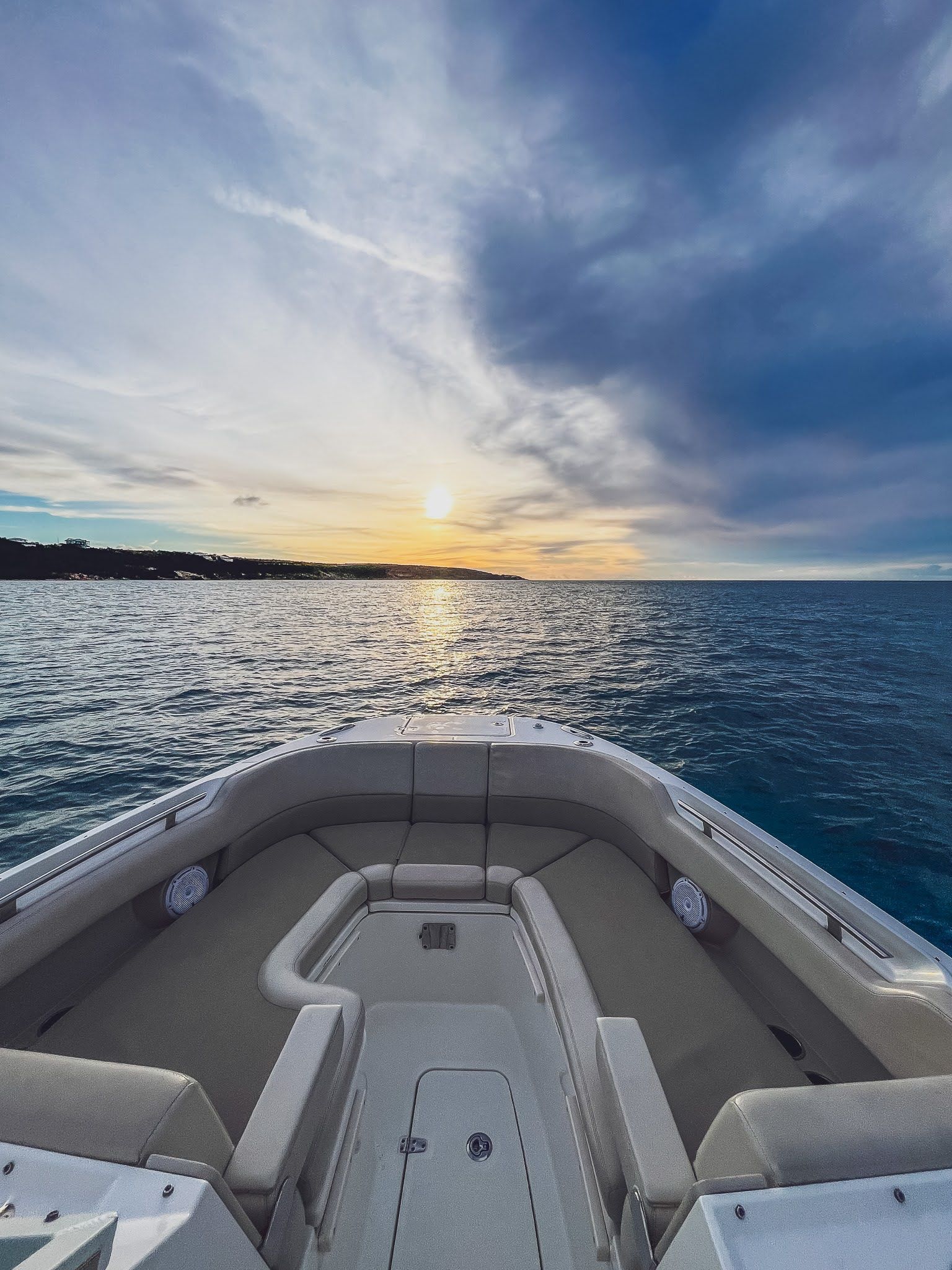 A boat is floating on top of a large body of water at sunset.
