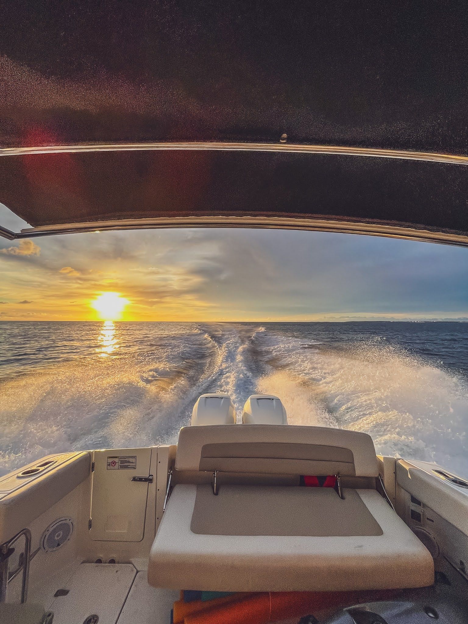 A boat is going through the ocean at sunset.