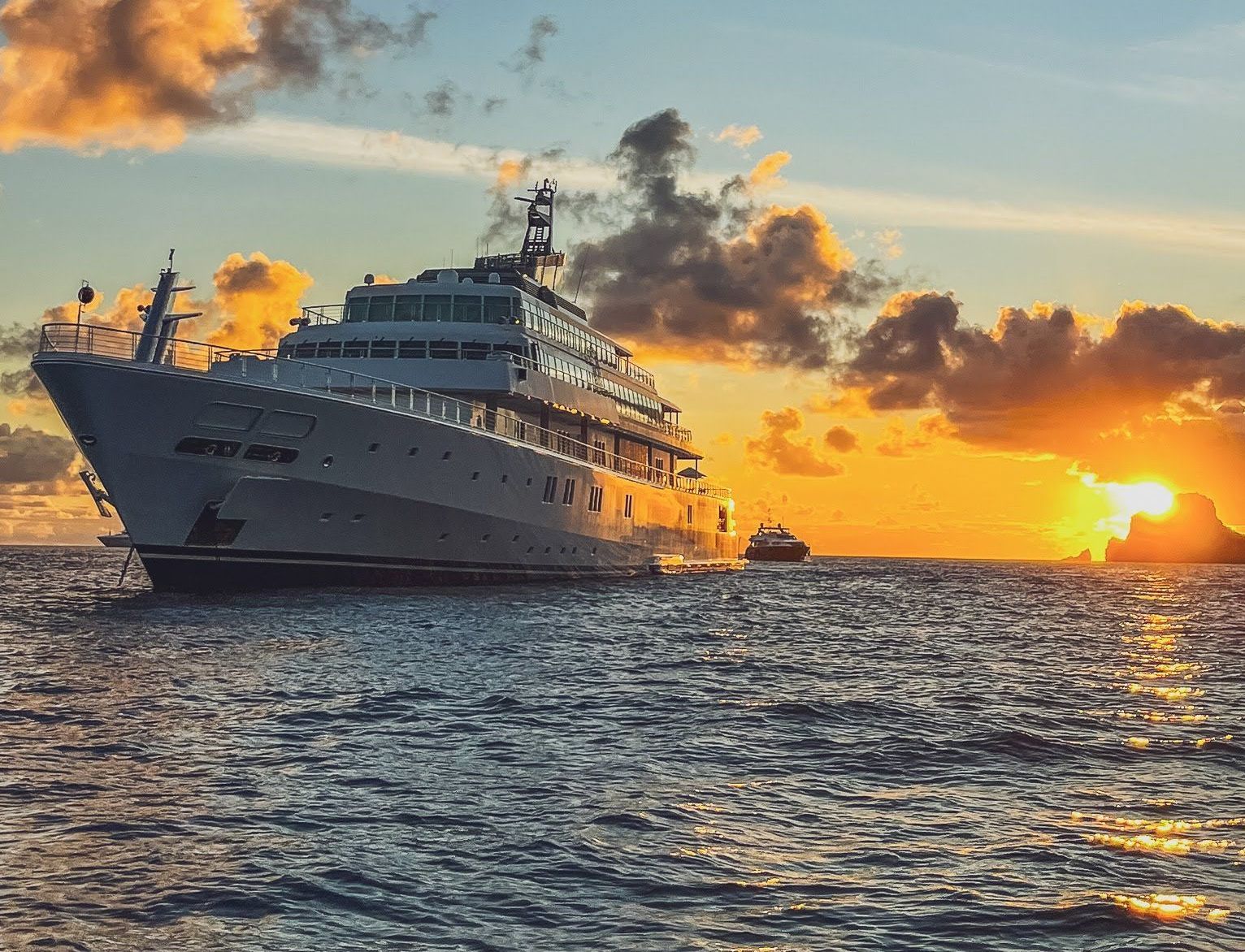 A large cruise ship is floating on top of a large body of water at sunset.