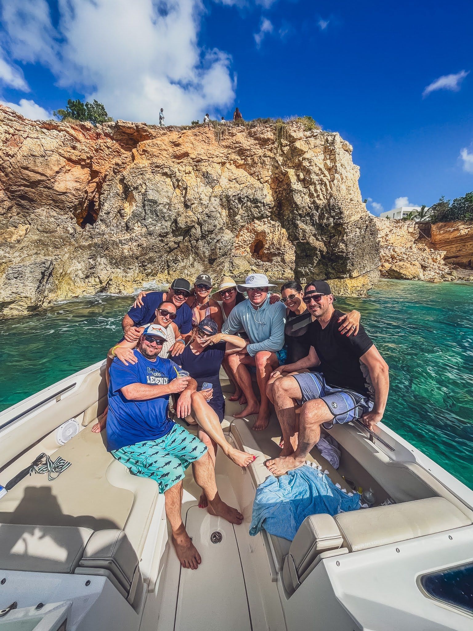 A group of people are sitting on the back of a boat in the ocean.