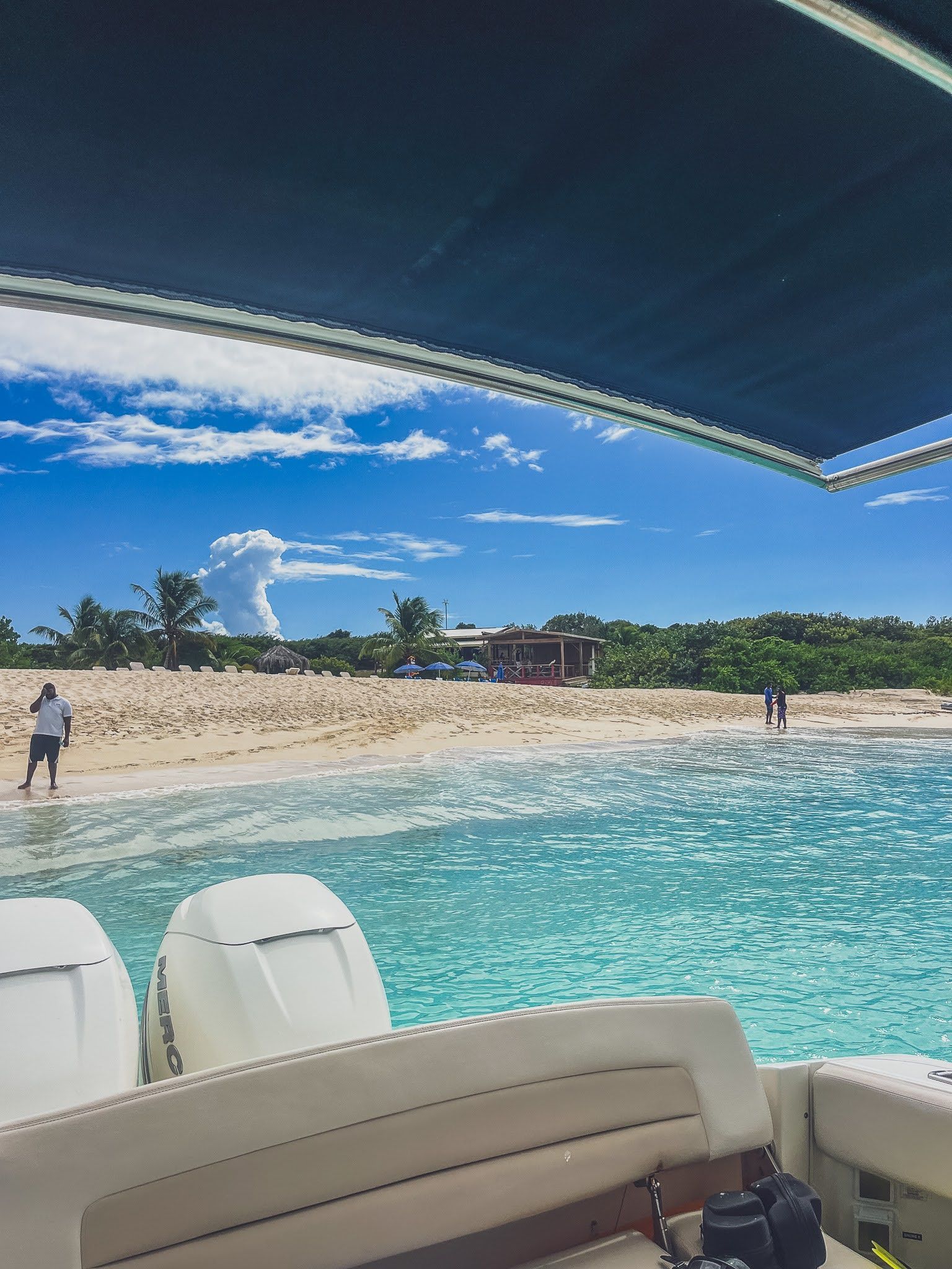 A view of a beach from the back of a boat.