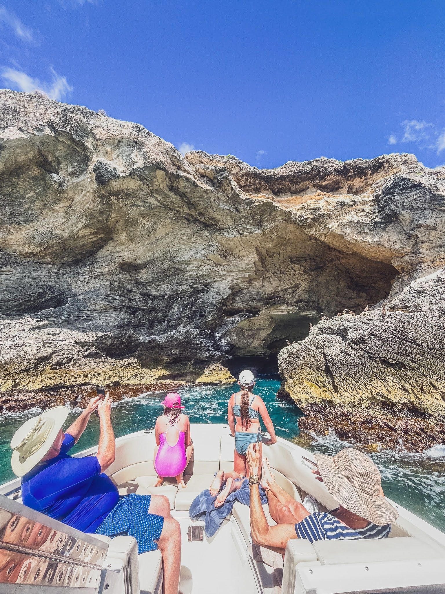 A group of people are sitting on the back of a boat in the ocean.