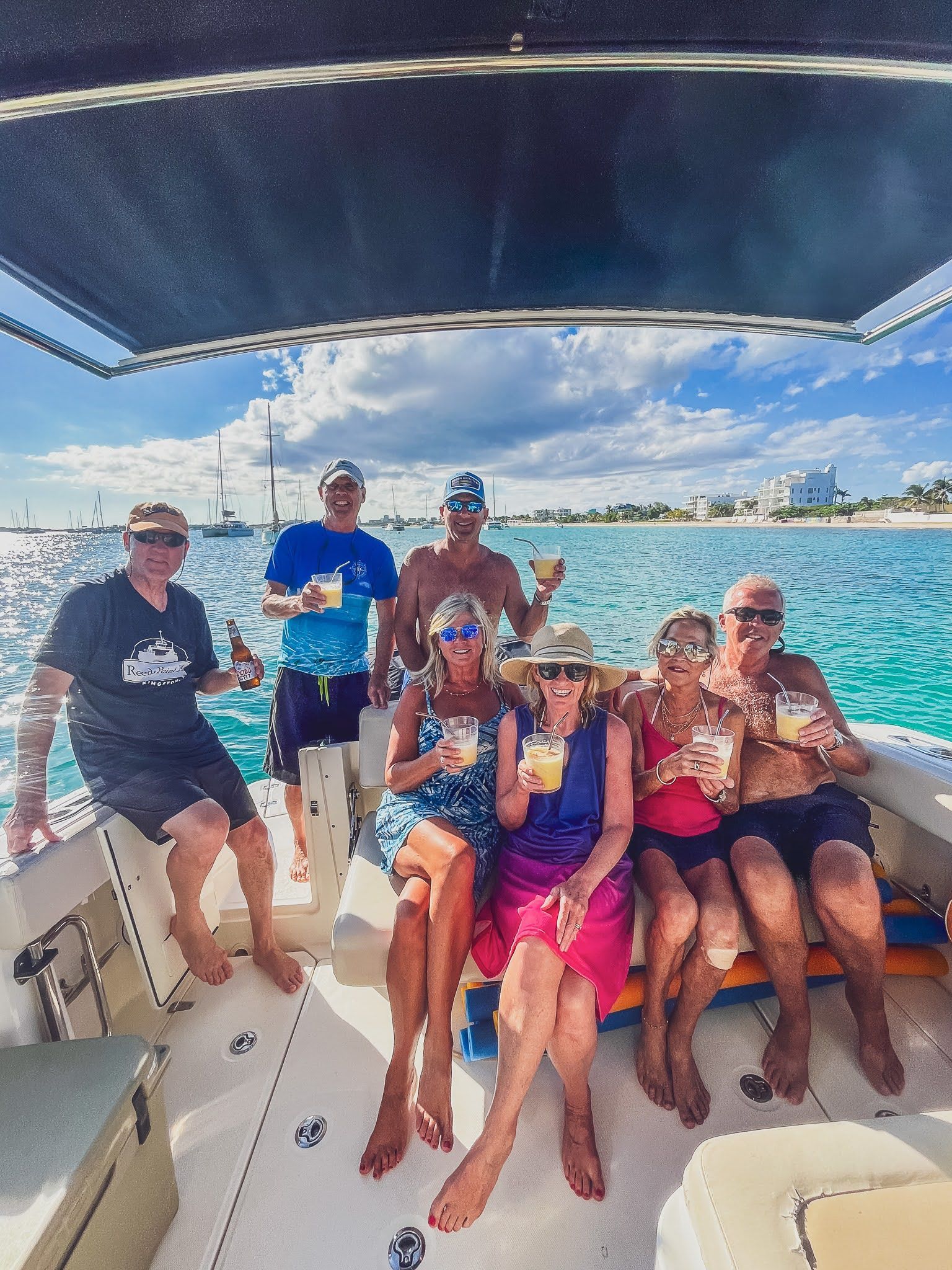 A group of people are sitting on a boat holding drinks.