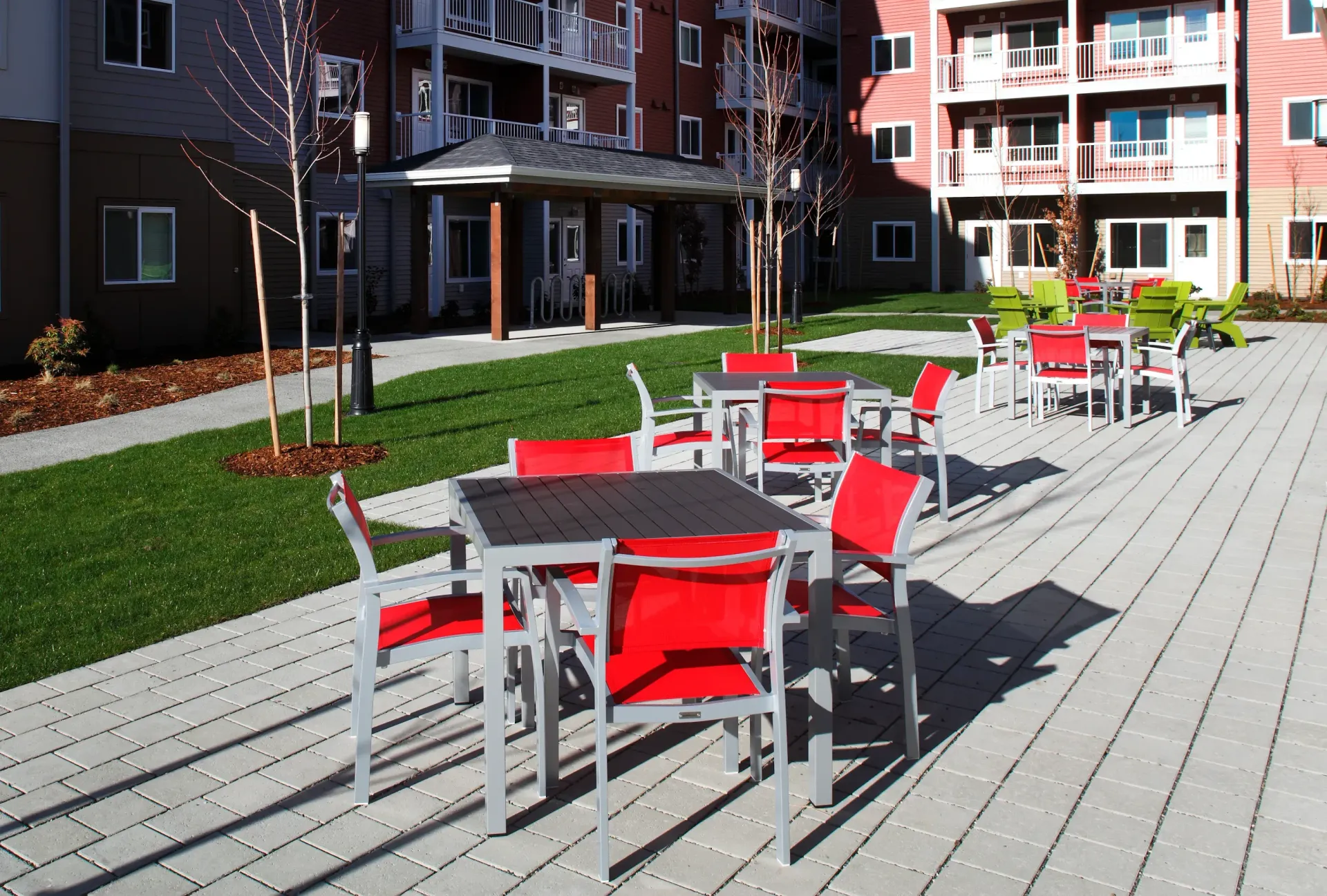 Outdoor communal courtyard with red and green seating tables in an apartment complex.