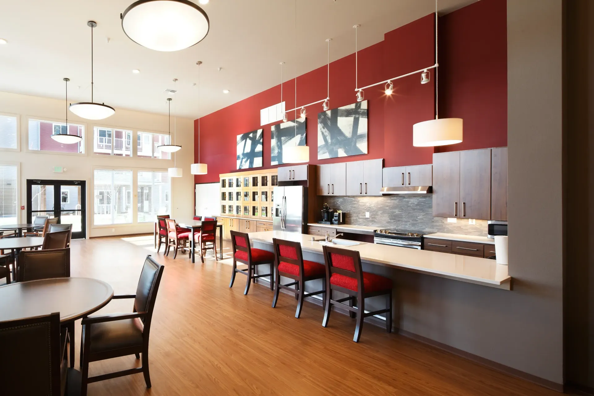 Modern community kitchen and lounge with red accent wall and island seating.