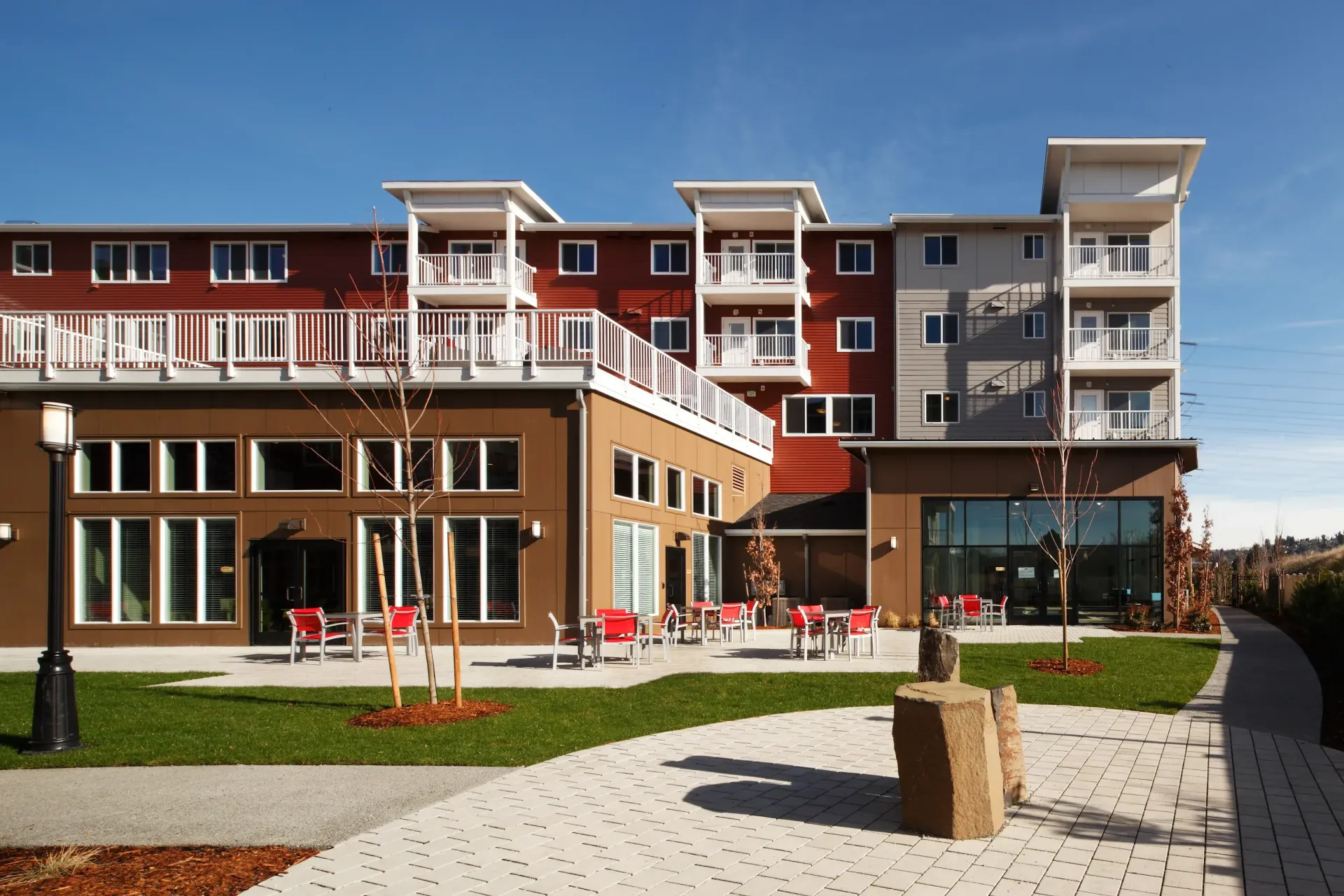 Exterior view of a modern multifamily building with a courtyard and outdoor seating.