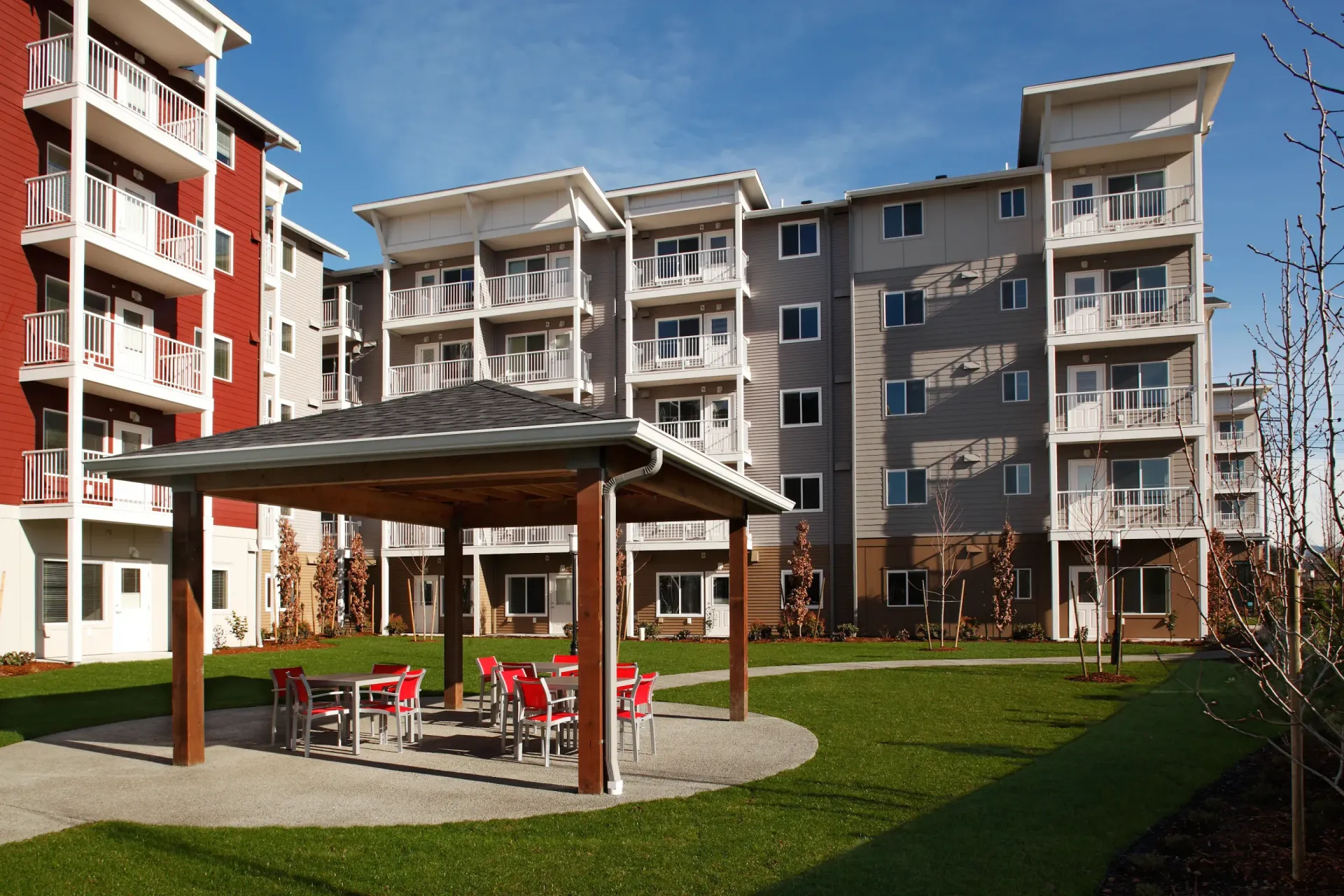 Outdoor community courtyard with a wooden pavilion and seating surrounded by apartment buildings.