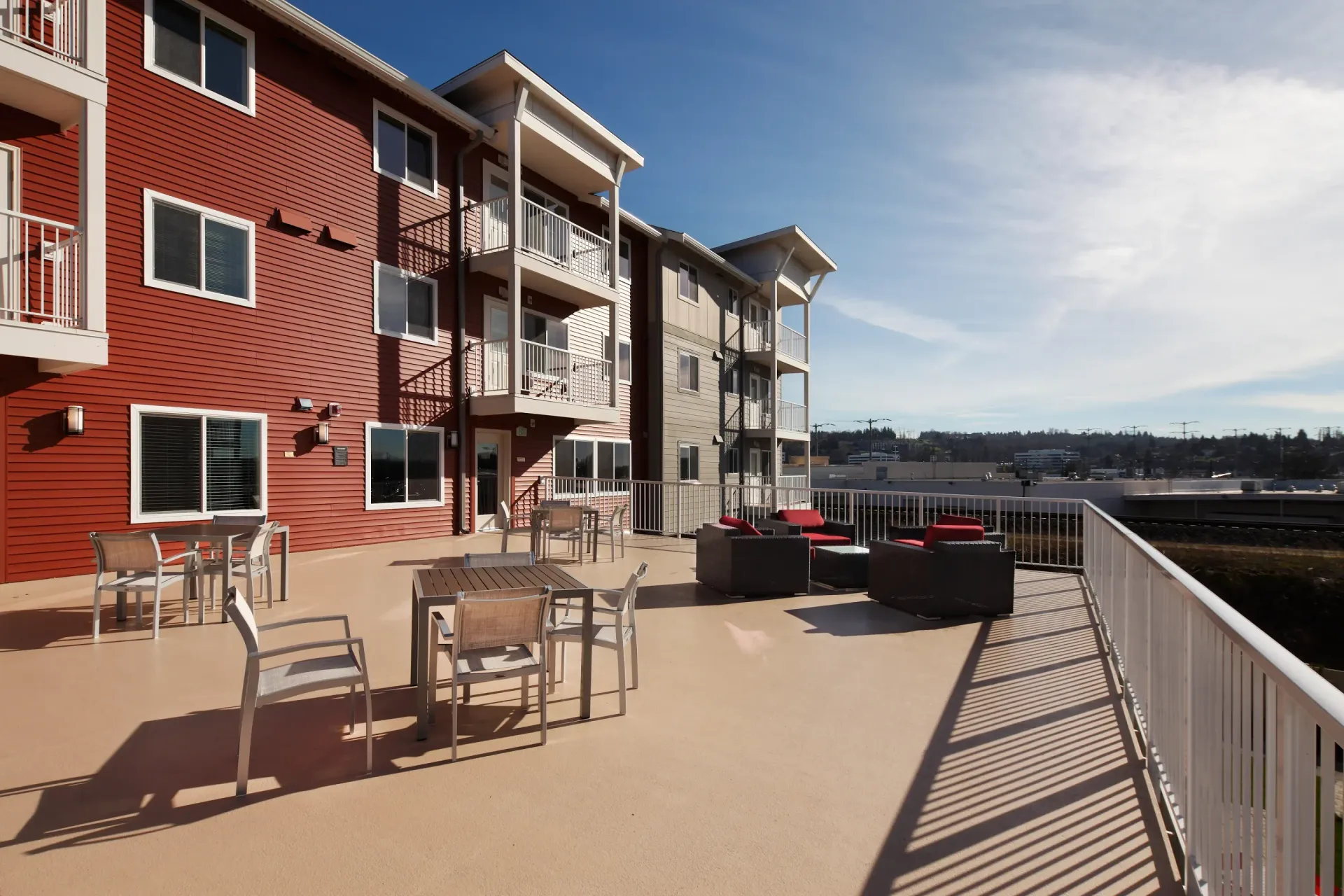 Rooftop terrace at a red apartment building with tables, chairs and lounge seating.