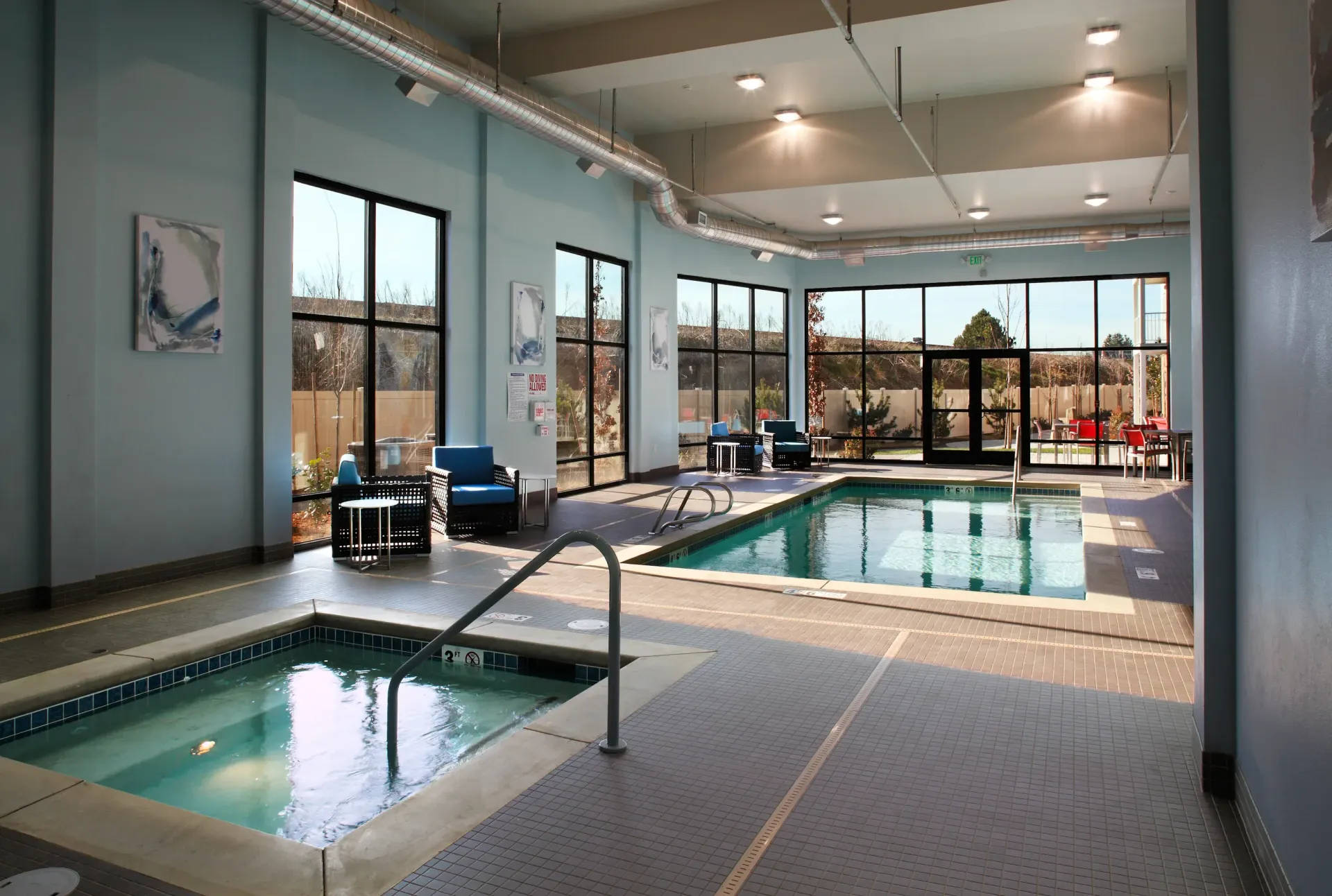 Indoor community pool area with lounge seating and large windows.